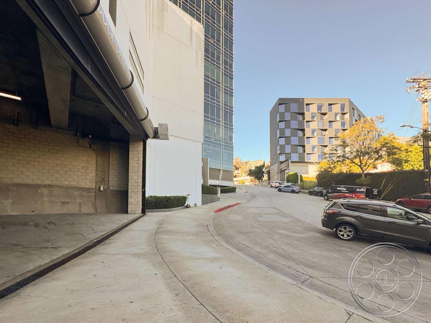 Sunset Storefront - paved driveway, exposed concrete wall, urban setting, steel railing, elevated view, curved driveway, eco-friendly materials, high-rise buildings, textured plaster wall, modern architectural design, glass window facade, exterior signage, contemporary building, concrete ramp, residential parking area, multi-family housing, landscaped sidewalk, stone planter box