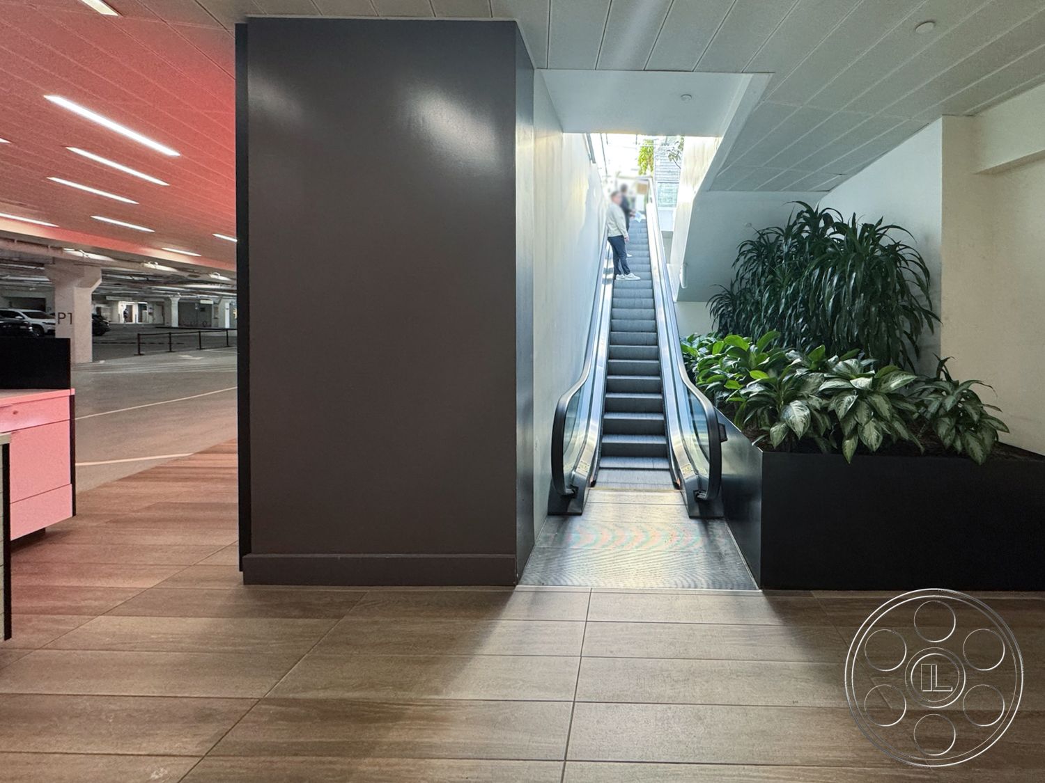 Sunset Storefront - minimalist design elements, open space design, glass railings, bright natural lighting, polished tile flooring, large potted plants, dimensional wall features, modern architectural details, interior escalator, floor tiles, gray wall treatment, commercial parking structure