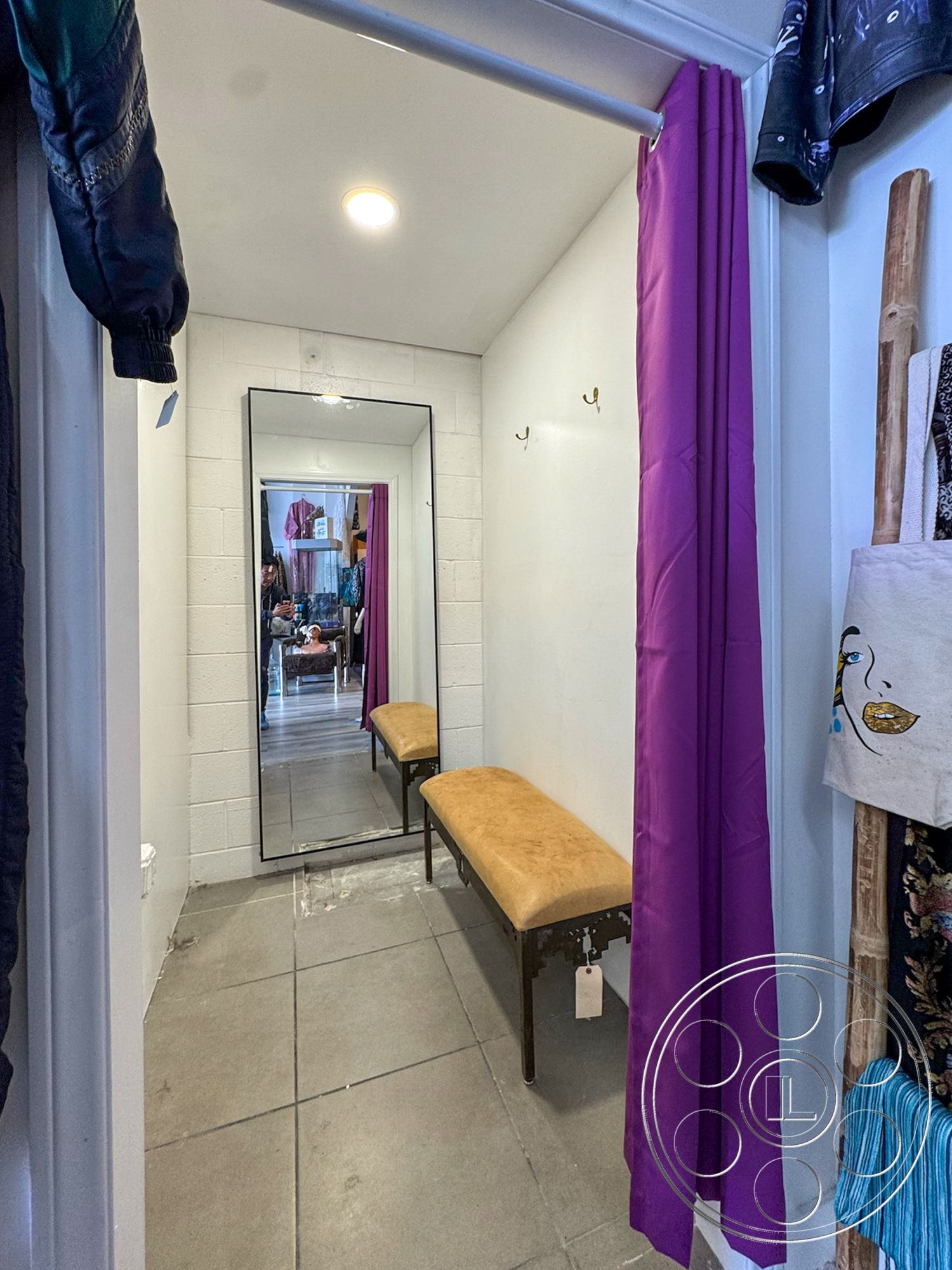 Melrose Store - minimalist design, full-length mirror, ambient recessed lighting, exposed concrete block walls, gray porcelain tile flooring, small entryway bench, purple fabric curtain, wall-mounted hooks, functional mudroom space