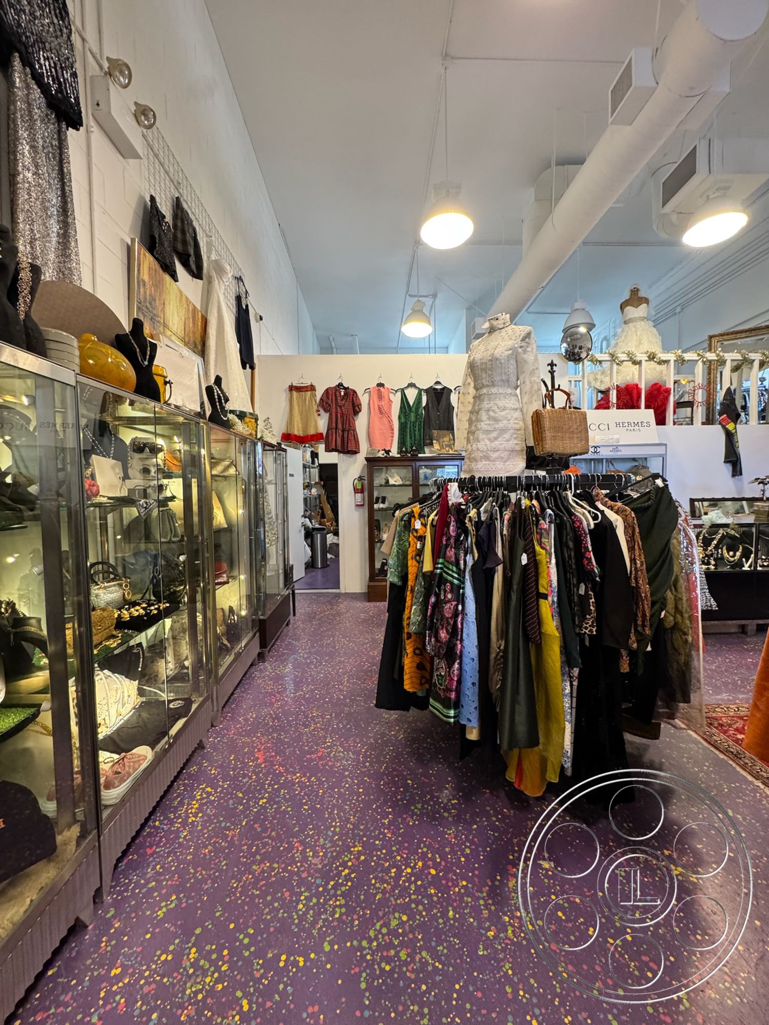 Melrose Store - high ceilings, polished concrete flooring, glass display cabinets, white painted walls, exposed brick accent wall, open interior layout, urban retail setting, vintage clothing racks, concrete floor with color speckles, retail display cases, modern overhead lighting, industrial style ceiling with ducts, colorful fabric garments, shopping area, fashion boutique interior