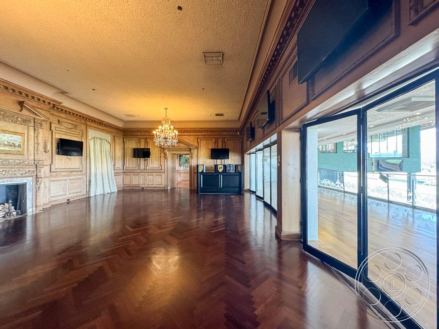 Arcadia Race Track - interior hardwood herringbone flooring, exterior large glass sliding doors, ornate wood paneling wall treatment, decorative chandelier lighting fixtures, exposed ceiling with detailed moldings, fireplace with classic mantel design, elegant sheer curtains for window treatment, built-in wall-mounted television units, luxury lounge space with spacious layout, multi-functional room with great natural light, traditional design elements with modern finishes