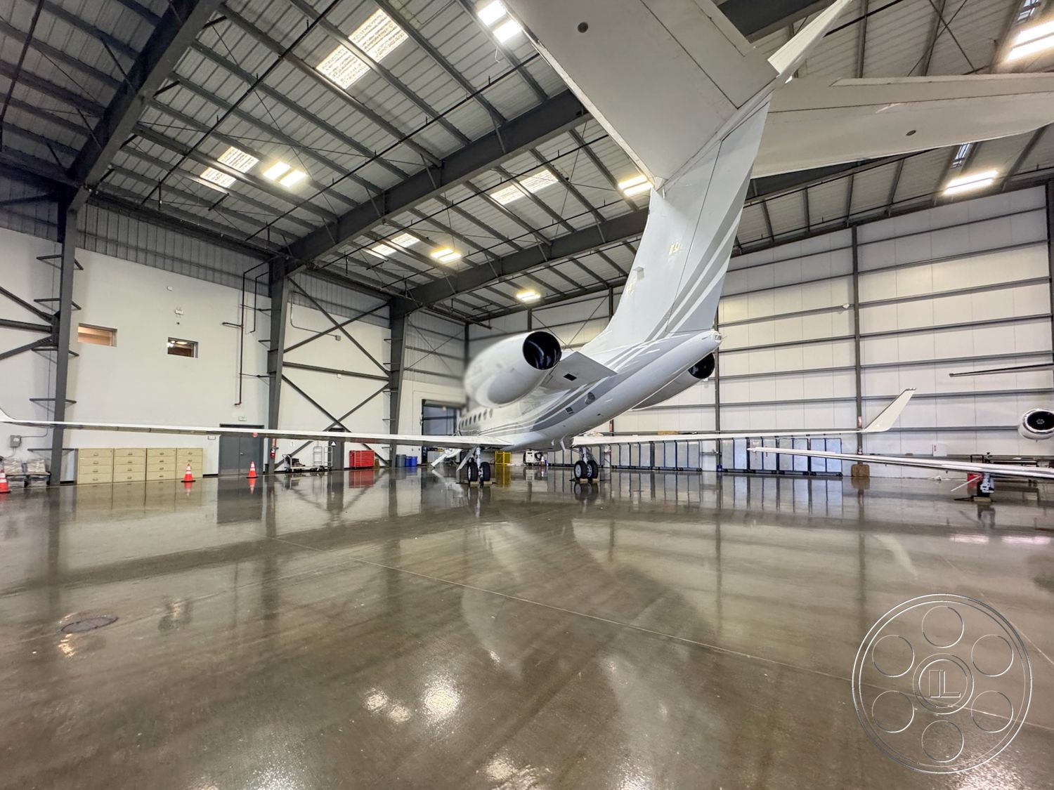 HW Hangar - industrial lighting fixtures, concrete polished floor, steel frame construction, open floor layout, aircraft parking area, aircraft maintenance space, tarmac view, large glass hangar doors, aircraft service area, metal building structure, high ceiling hangar interior, hangar space for aircraft, metal wall paneling, helicopter area, ventilated aircraft storage, exposed beams and trusses, hangar with side windows, exterior hangar facade, aircraft loading zone, interior equipment storage