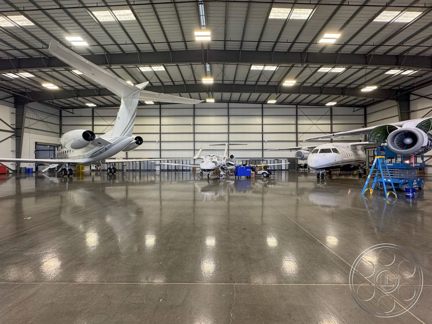 HW Hangar - sloped roof design, large glass entry doors, exterior hangar structure, aircraft maintenance area, high ceiling industrial space, hangar lighting fixtures, reflective epoxy flooring, metal panel walls, ceiling truss system, custom aircraft parking layout