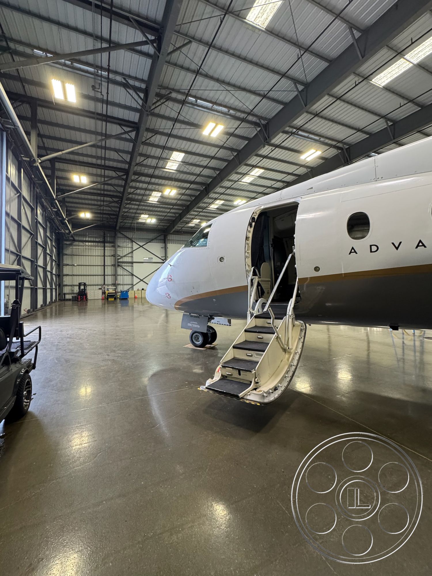 HW Hangar - polished concrete flooring, spacious open layout, functional industrial design, aircraft maintenance area, metal aircraft hangar interior, high ceiling with exposed steel trusses, large industrial LED lighting, hangar bay with open space, aircraft entry steps, contemporary aviation facility, doorway access for aircraft, well-lit aviation workspace, tarmac access for ground vehicles, garage-style vehicle storage, maintenance tools and equipment storage