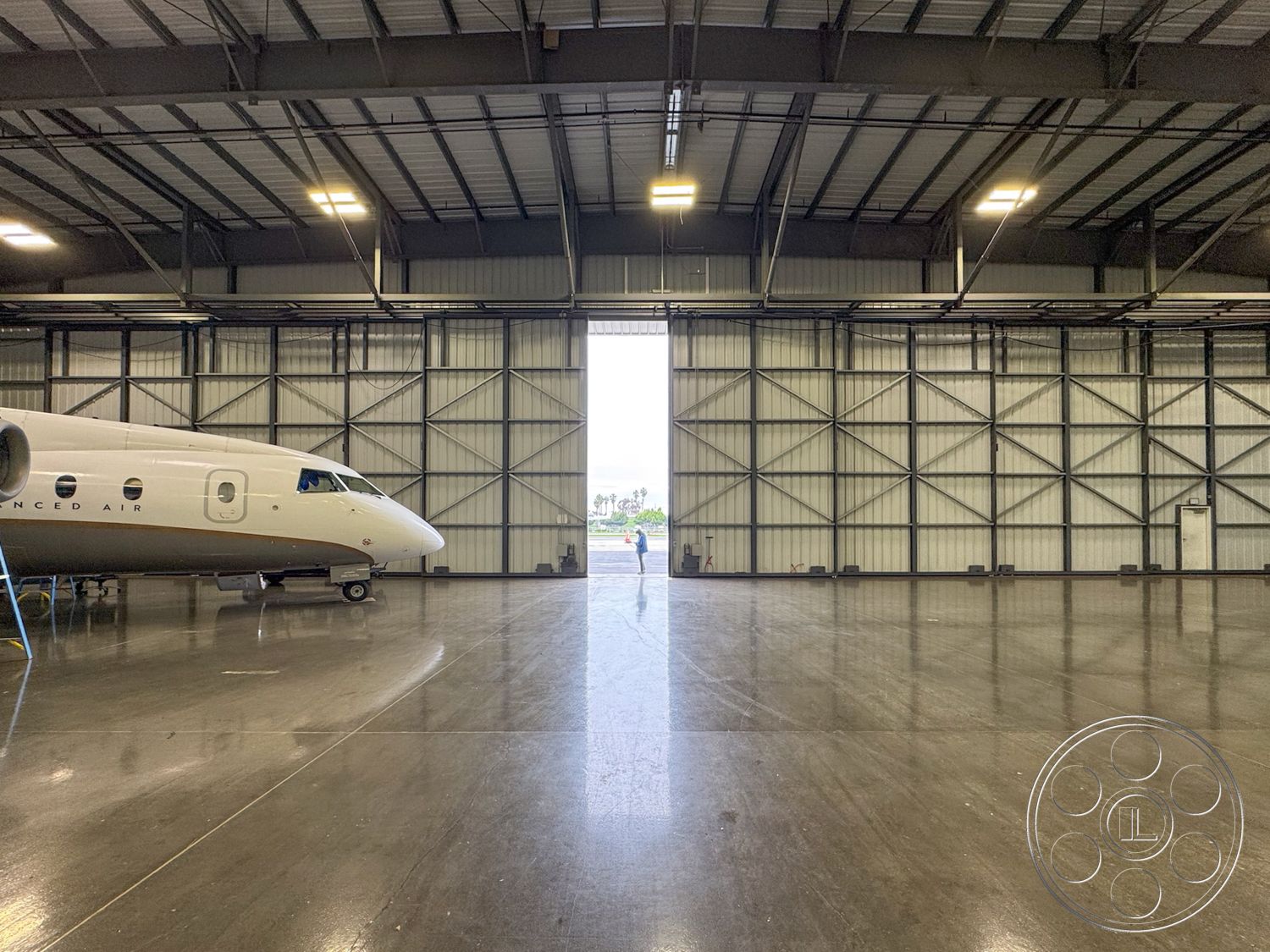 HW Hangar - high ceilings, open floor plan, polished concrete flooring, industrial lighting, metal siding, shared workspace, steel frame construction, aircraft parking area, large hangar door, aircraft maintenance area, hangar interior, exposed steel trusses, commercial aviation environment, hangar space, mechanical room, elevated access platform