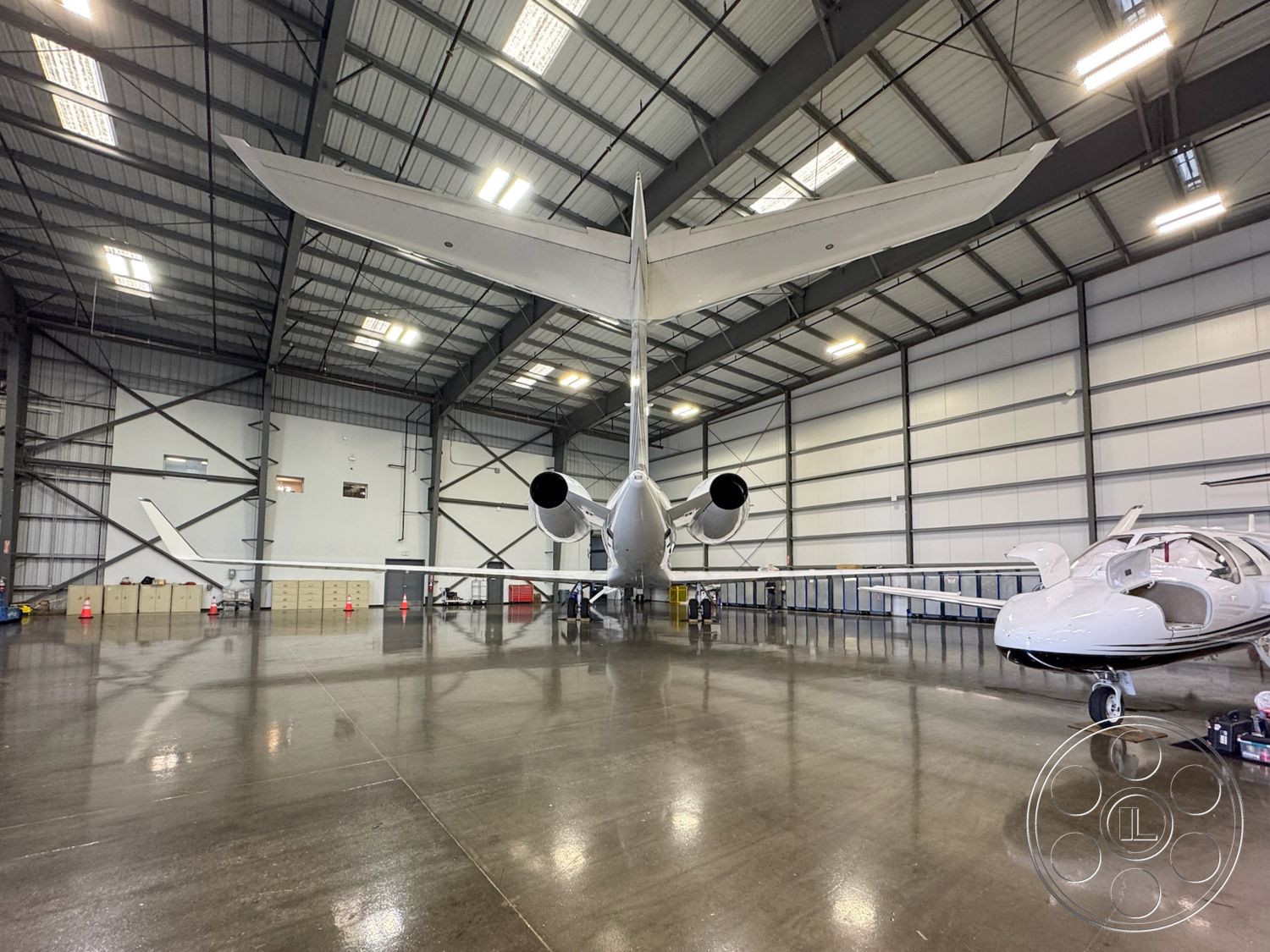 HW Hangar - open floor plan, interior space, industrial lighting fixtures, steel frame construction, spacious interior layout, aircraft storage space, large hangar doors, modern aviation facility, high ceiling with exposed trusses, concrete floor with high gloss finish, metal warehouse structure, partitioned work areas, airplane maintenance area, efficient workflow design, natural light from high windows, hangar setting