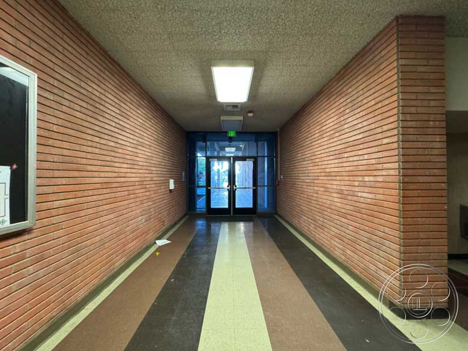 Old School - neutral color palette, exposed brick walls, textured plaster ceiling, modern architectural design, interior corridor, functional entryway space, commercial building hallway, concrete hallway flooring, detailed light fixtures, rectangular entry space, glass double door entry, linear floor pattern, large illuminated ceiling light