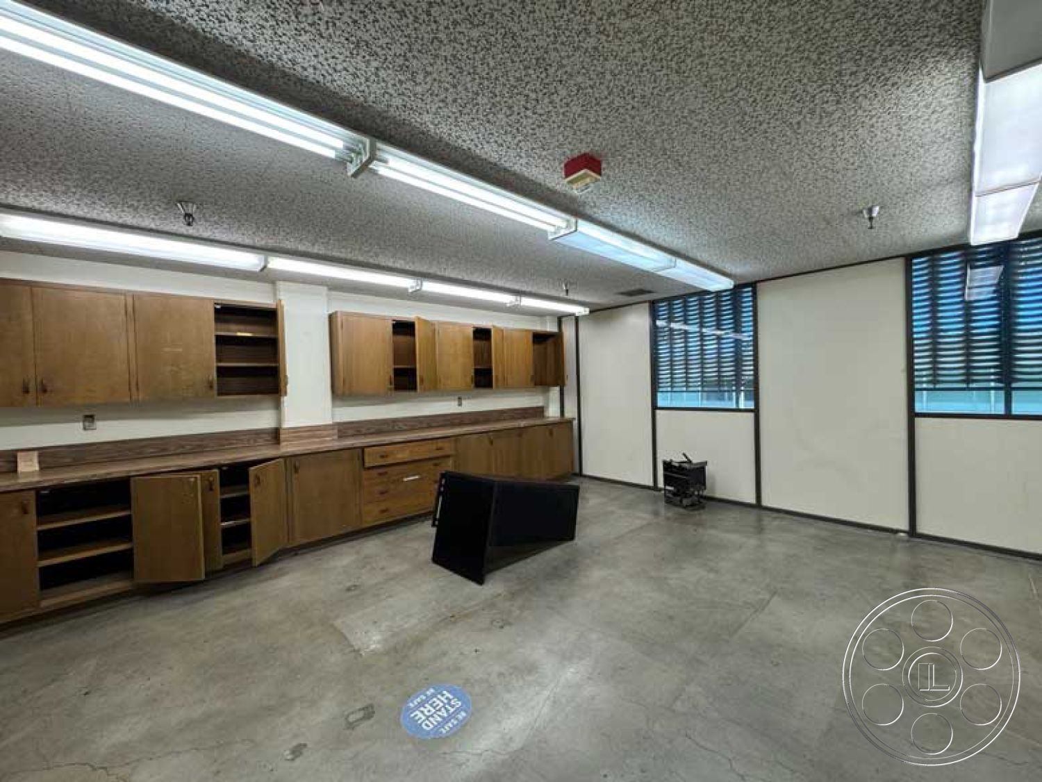 Old School - neutral color palette, modern lighting fixtures, wooden kitchen cabinets, minimalist room design, open floor layout, exposed concrete flooring, fluorescent ceiling lights, laminate countertop, industrial-style elements, horizontal window slats, contemporary workspace interior, functional cabinetry