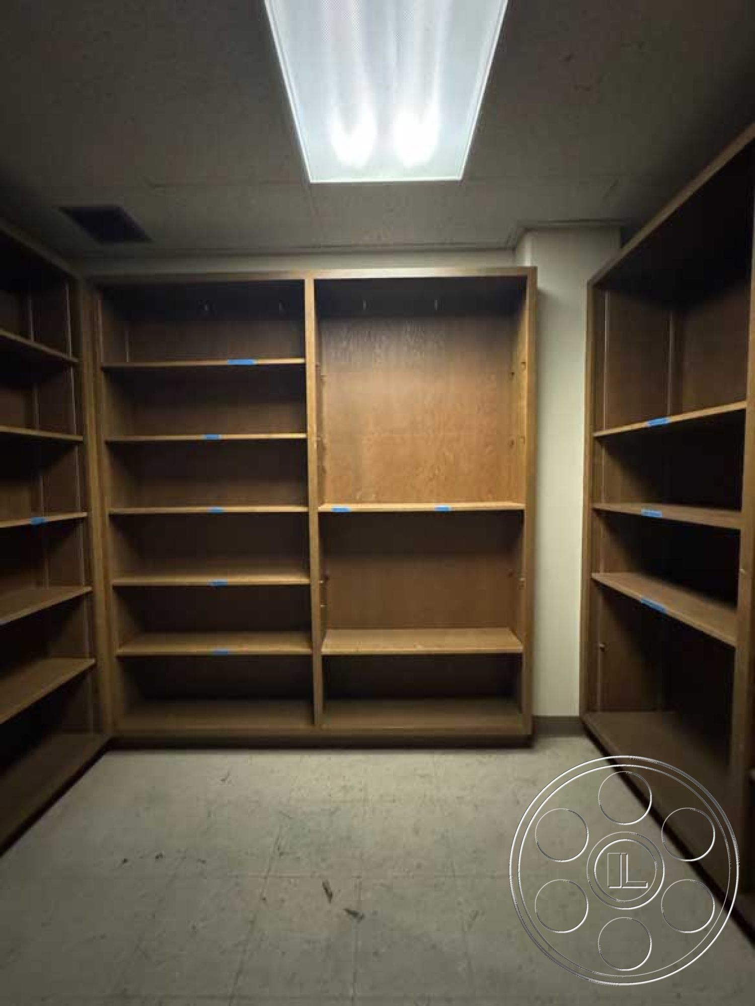 Old School - neutral wall color, built-in bookshelves, overhead fluorescent lighting, minimalist room design, interior wood shelving units, exposed ceiling lights, sparse room layout, natural wood grain finish, interior laminate flooring, empty storage space