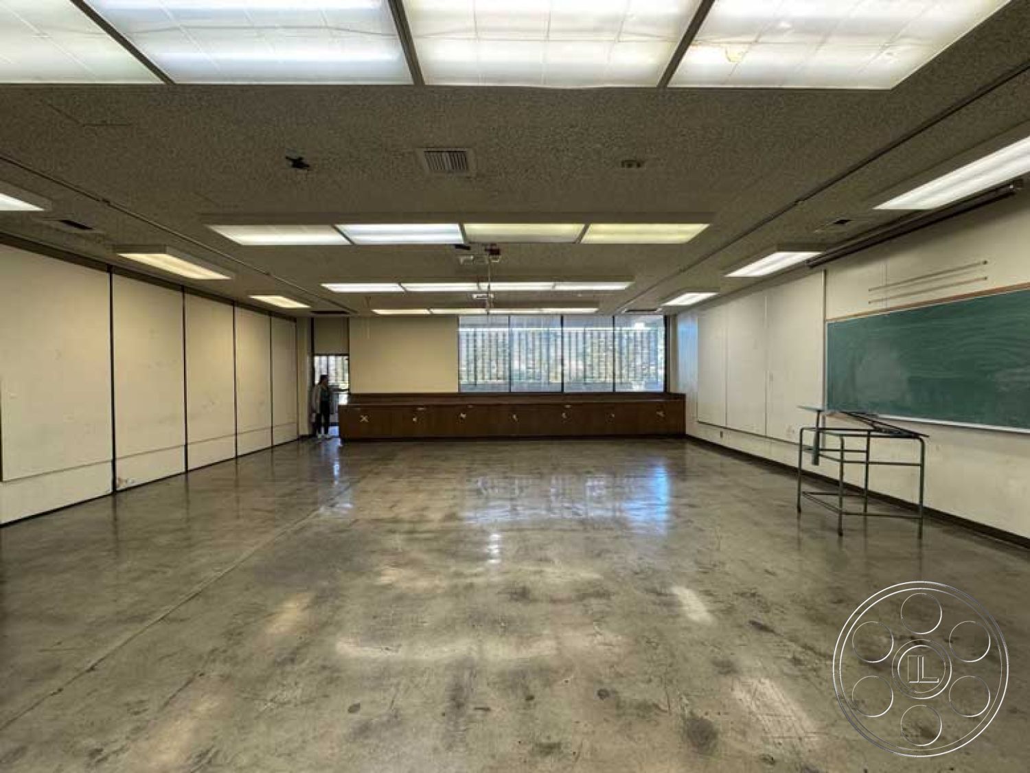 Old School - minimalist architectural style, drop ceiling with fluorescent lighting, interior classroom design, functional educational environment, chalkboard wall treatment, open classroom space, exposed aggregate concrete floor, wood cabinetry along walls, glass windows with metal frames