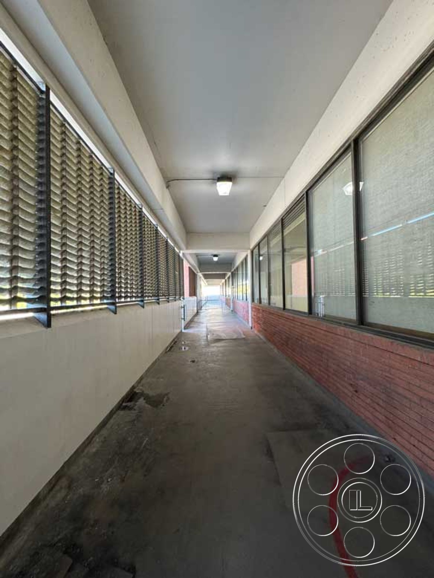 Old School - neutral color palette, minimalist aesthetic, concrete flooring, exposed brick wall, industrial design elements, rectangular shapes, commercial architecture, overhead fluorescent lighting, exterior corridor walkway, large window panels, horizontal slatted blinds, straight walkway layout