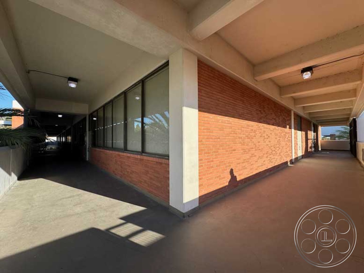 Old School - large glass windows, urban setting, exposed brick wall, industrial lighting fixtures, modern architectural style, natural light integration, flat roof structure, minimalist exterior design, spacious corridor layout, open-air passage, exterior concrete flooring, concrete beams, seamless transition from indoor to outdoor