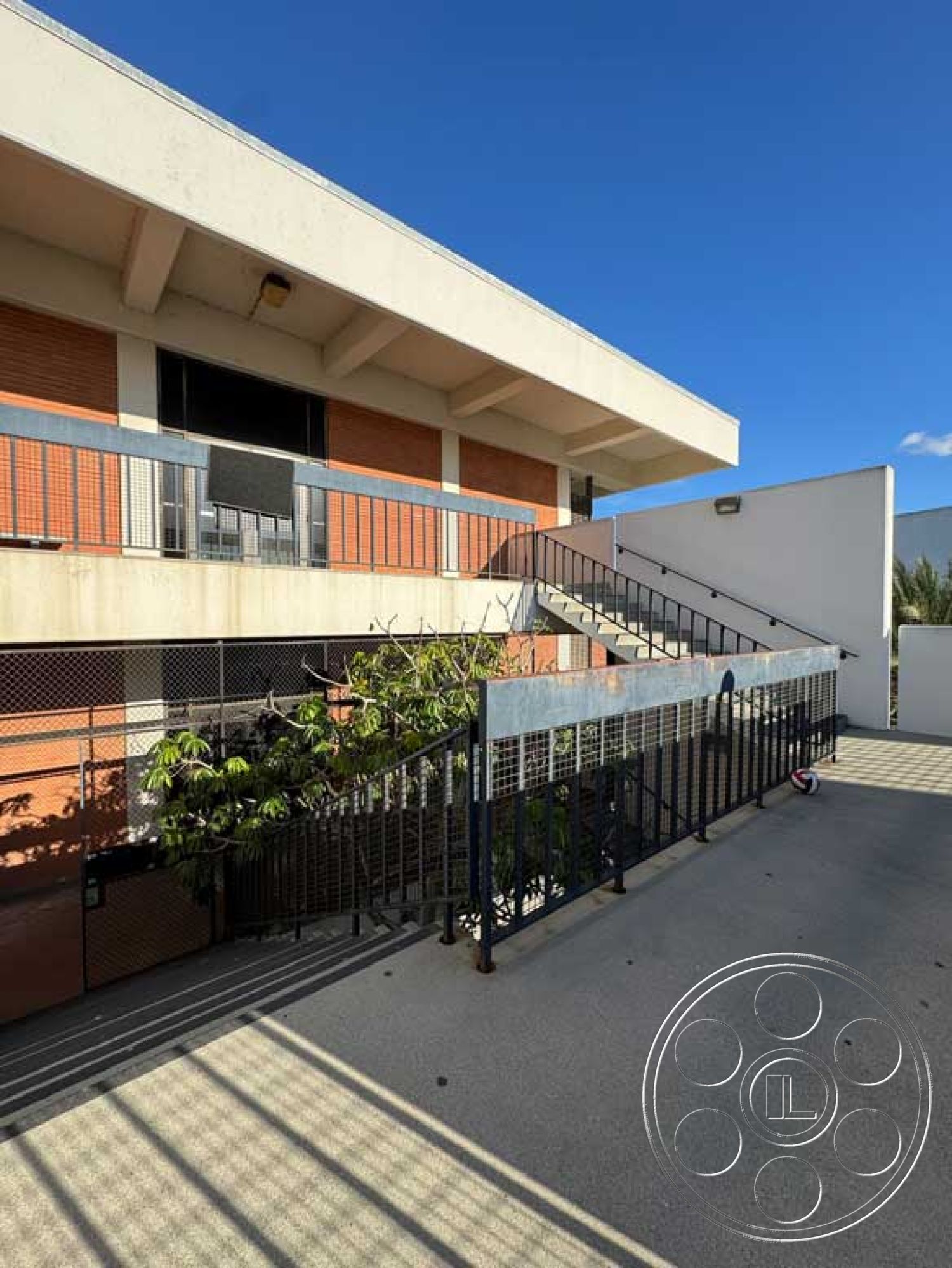 Old School - landscaped greenery, urban setting, modern architectural style, flat roof design, steel support beams, metal fence accents, metal railing details, rectangular building shape, exposed brick exterior walls, exterior lighting fixtures, concrete stair treads, open-air staircase, permeable paving, glass balcony guardrails, cement courtyard flooring, large window placements