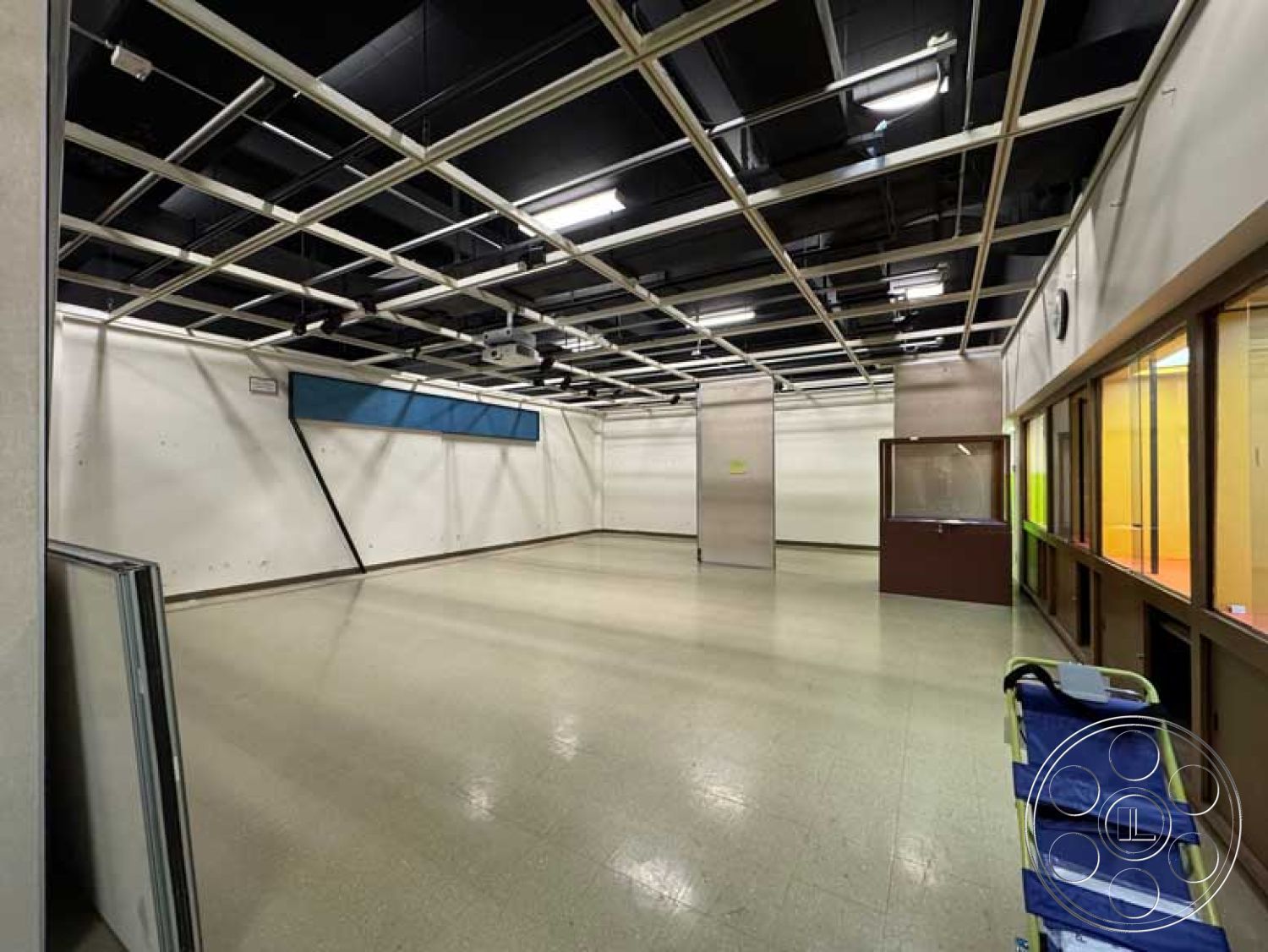 Old School - open floor plan, interior space, plain white walls, built-in cabinetry, vinyl tile flooring, drop ceiling with grid tiles, windowed observation area, illuminated ceiling lights, flexible space for multiple functions, modular wall partitions