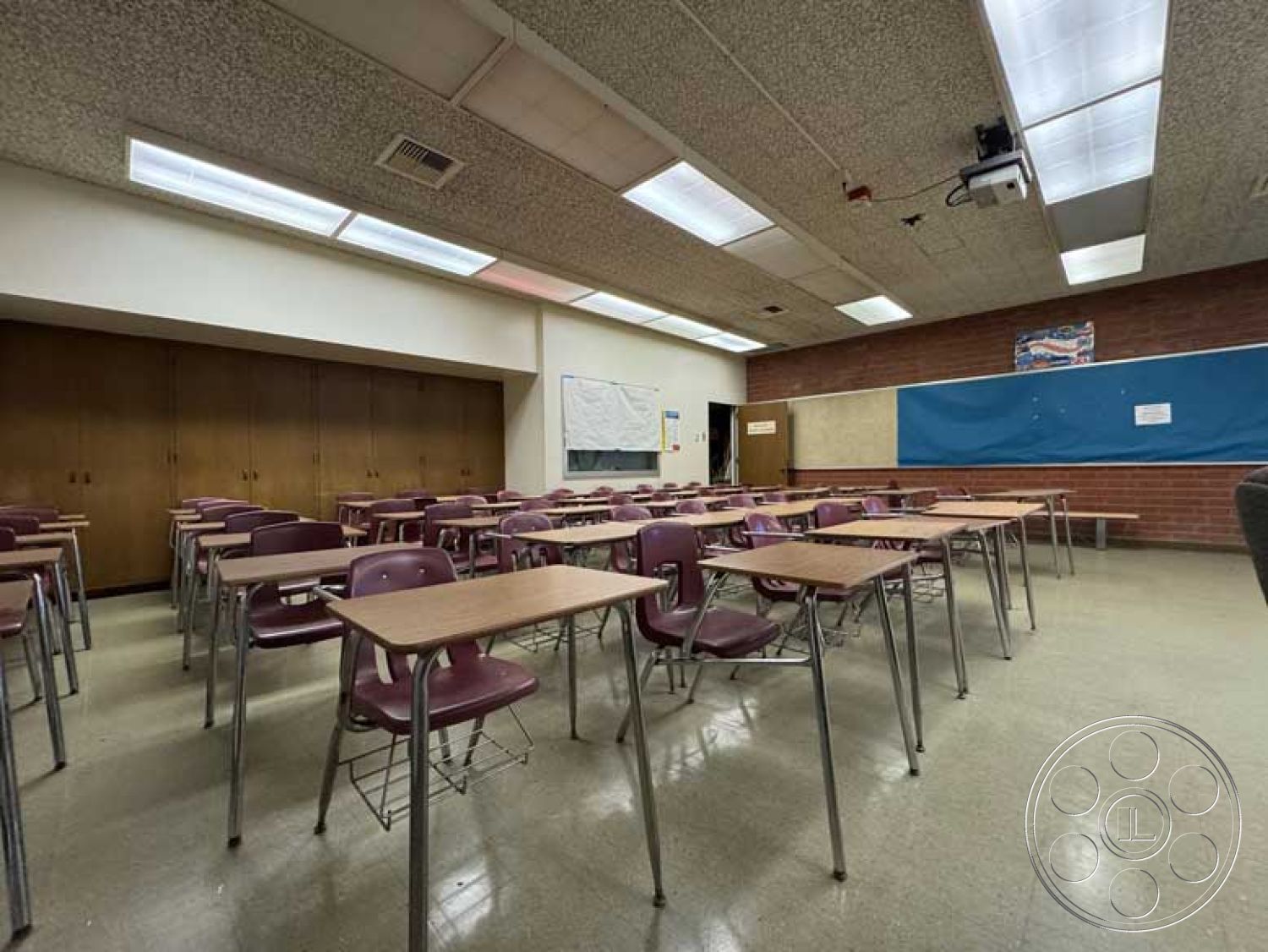 Old School - open layout, textured wall finish, laminate flooring, brick accent wall, educational environment, overhead fluorescent lighting, drop ceiling tiles, whiteboard wall, interior classroom, chalkboard section, projector mounting, wood veneer storage cabinets, metal frame student desks, plastic molded chairs