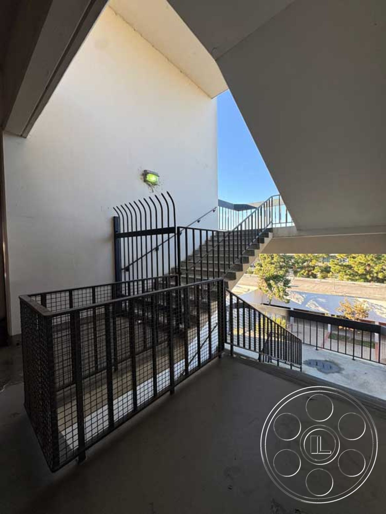 Old School - minimalist aesthetic, concrete floor, exposed concrete walls, urban setting, outdoor view, built-in lighting, modern architectural design, industrial style elements, interior staircase, metal spiral staircase, concrete stair treads, metal railing with mesh, open-air landing, dual-level entrance, guarded access stairway