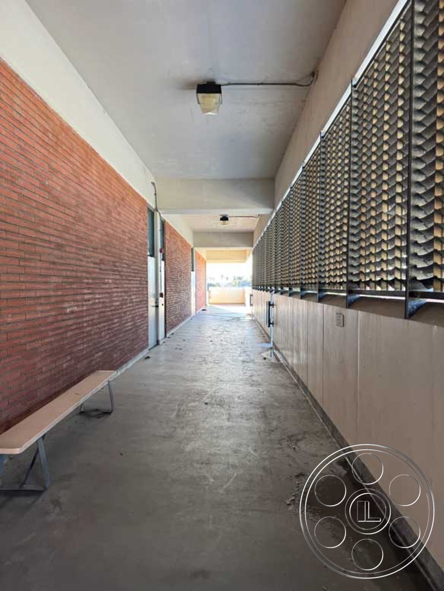 Old School - flat ceiling with recessed lighting, exposed brick accent wall, minimalist architectural details, smooth plaster walls, linear lighting fixtures, concrete walkway flooring, interior corridor design, metal lattice screen panels, bench seating with metal supports, industrial style corridor, urban building interior, door access points, public passageway design
