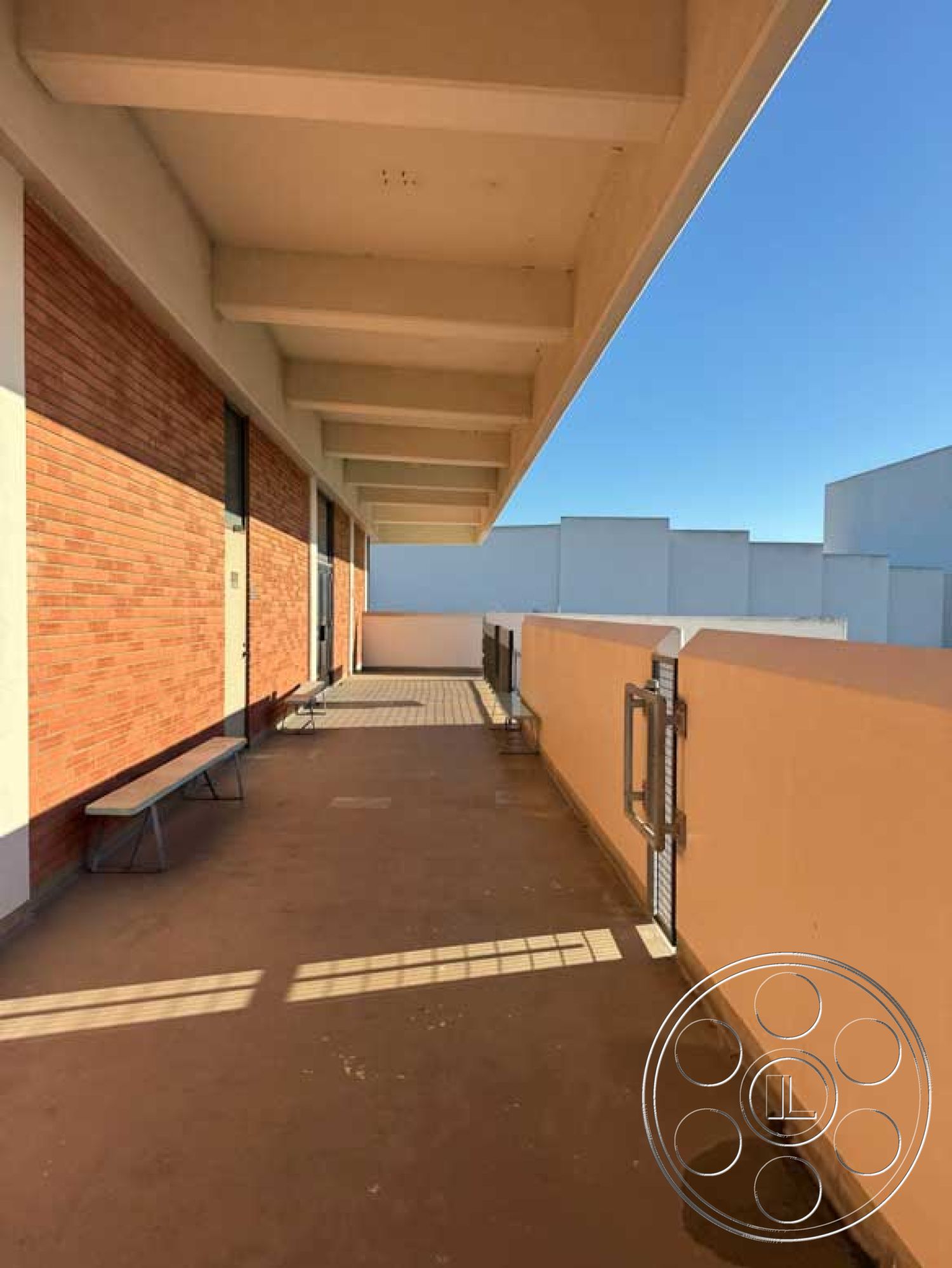 Old School - minimalist design, large glass windows, horizontal lines, textured concrete surface, concrete patio flooring, industrial architectural style, metal handrail details, exterior brick wall, modern building facade, urban rooftop terrace, exposed concrete ceiling beams, open-air walkway, bench seating area, sun-lit outdoor space