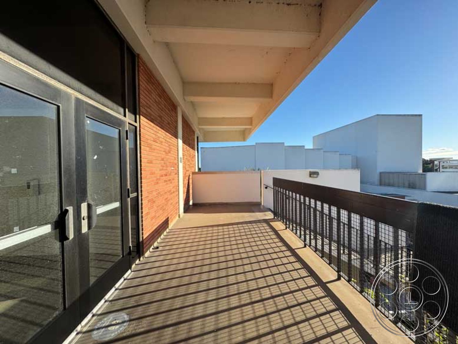 Old School - modern architectural style, floor-to-ceiling glass doors, urban setting with city view, metal railing detail, minimalist design features, rectangular balcony shape, exterior balcony with concrete flooring, exposed brick wall surface, roof overhang element, open air balcony space