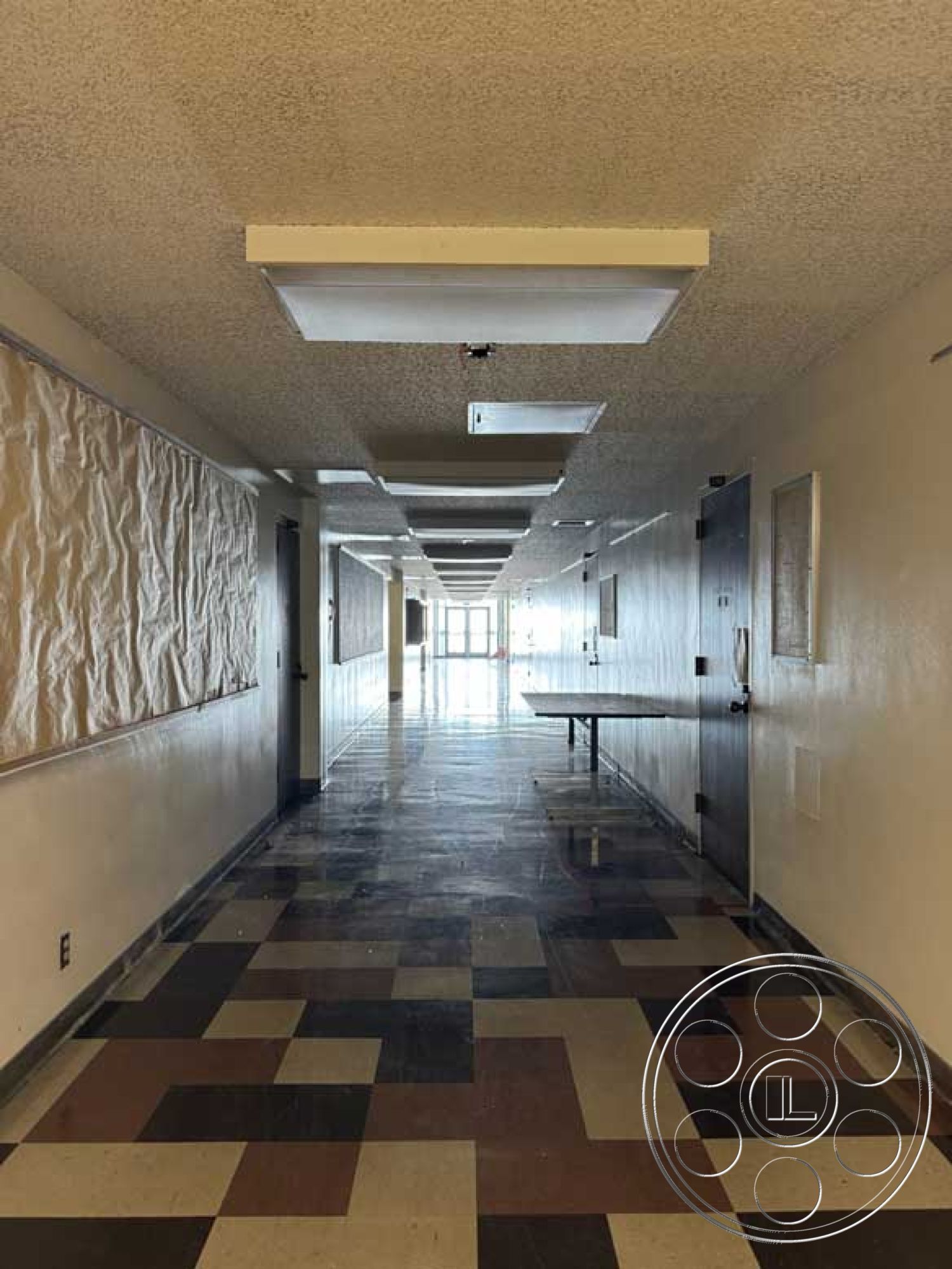 Old School - textured wall panels, neutral wall color, empty space, textured plaster walls, accessible layout, interior corridor, double wooden doors, glossy vinyl flooring, long hallway layout, quadrant-patterned tile floor, drop ceiling panels with fluorescent lights, plain light fixture, contemporary institutional design, light-filled entryway