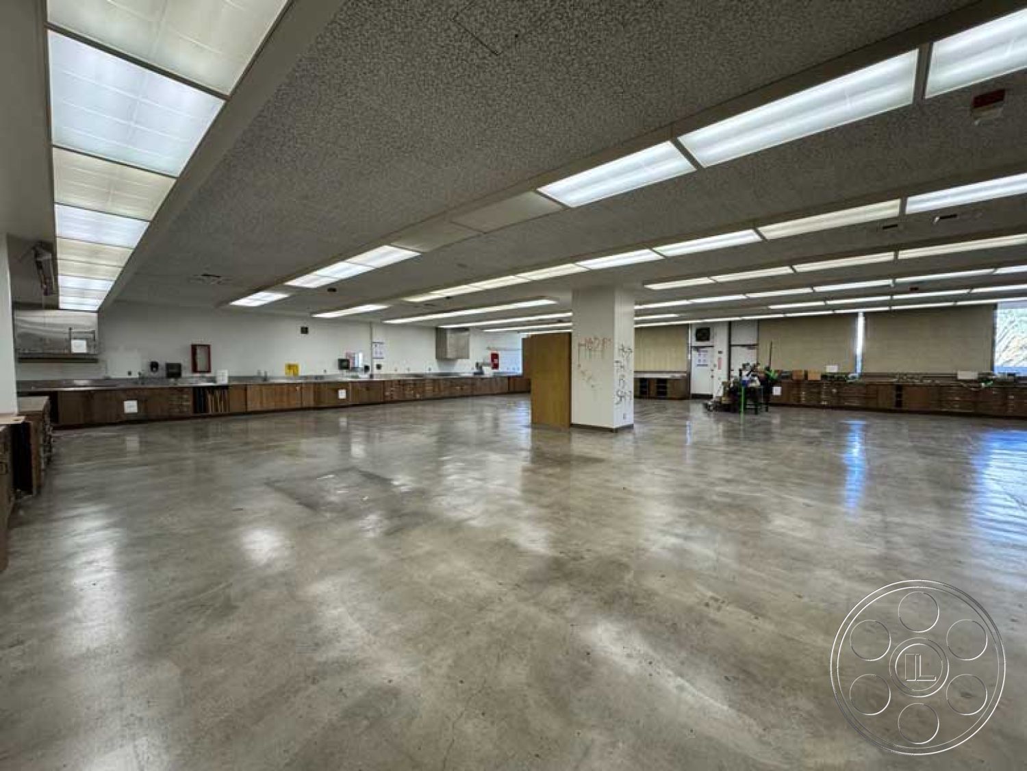 Old School - dark wood cabinetry, polished concrete flooring, minimalist interior design, textured acoustic ceiling tiles, open plan interior, multi-functional workspace, brightly lit workspace, functional layout design, industrial kitchen space, task lighting ceilings, large windowed walls, commercial kitchen environment, exposed beam ceiling architecture, modern utility area, oversized room dimensions, commercial-grade finishes