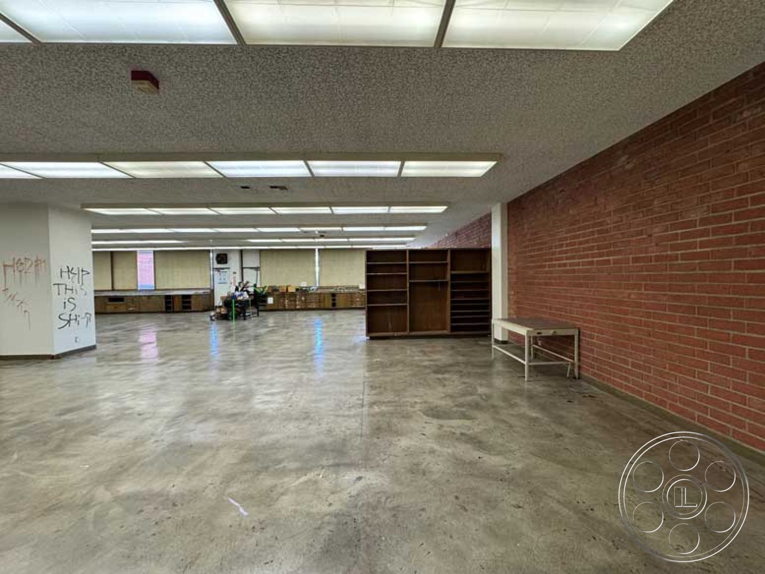 Old School - minimalist decor, polished concrete floor, large windows for natural light, exposed brick accent wall, open interior layout, urban interior setting, industrial style architecture, functional workspace area, drop ceiling with fluorescent lighting, built-in wooden shelving units, modern commercial space design, brightly lit exercise