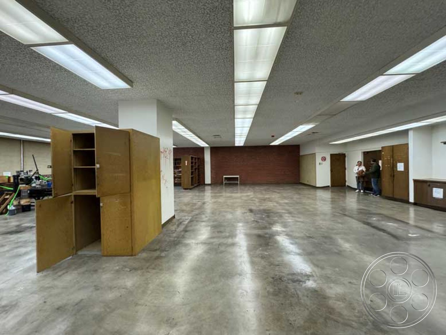 Old School - neutral color palette, open floor plan, floating shelves, functional layout, workshop area, concrete flooring, minimalist design elements, exposed brick accent wall, smooth plaster walls, commercial space interior, industrial style accents, flexible use space, large unobstructed space, ceiling fluorescent lighting, modern renovation potential, bulk storage cabinets, custom built-in bookcases