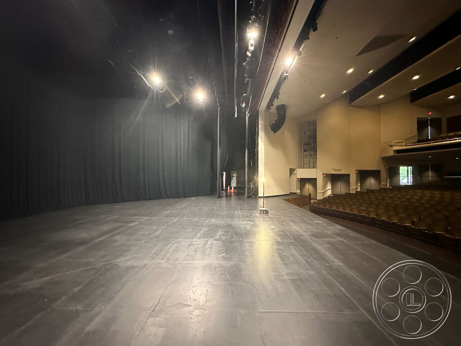 JT Theatre - theater stage interior, auditorium seating area, acoustic panel walls, blackout curtains, theater production environment, black semi-gloss stage floor, curtained backdrop wall, spotlights hanging from ceiling, soundboard control area, drama performance space, multi-purpose event space, lighting rigging system, accessible stage area, soundproof room adjacent, raised seating platform
