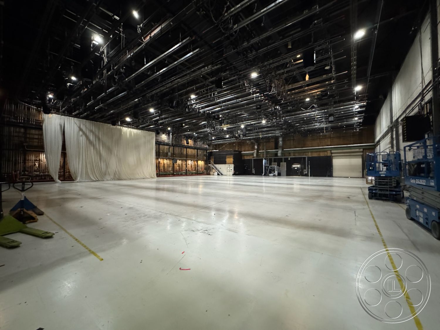 Stage 33 - neutral color palette, clean lines, open layout, concrete flooring, exterior space, industrial setting, high ceiling space, ceiling-mounted lighting fixtures, flexible usage space, black steel support structure, studio backdrop curtain, spacious studio area, loading dock entrance, movable equipment platforms, sound stage environment