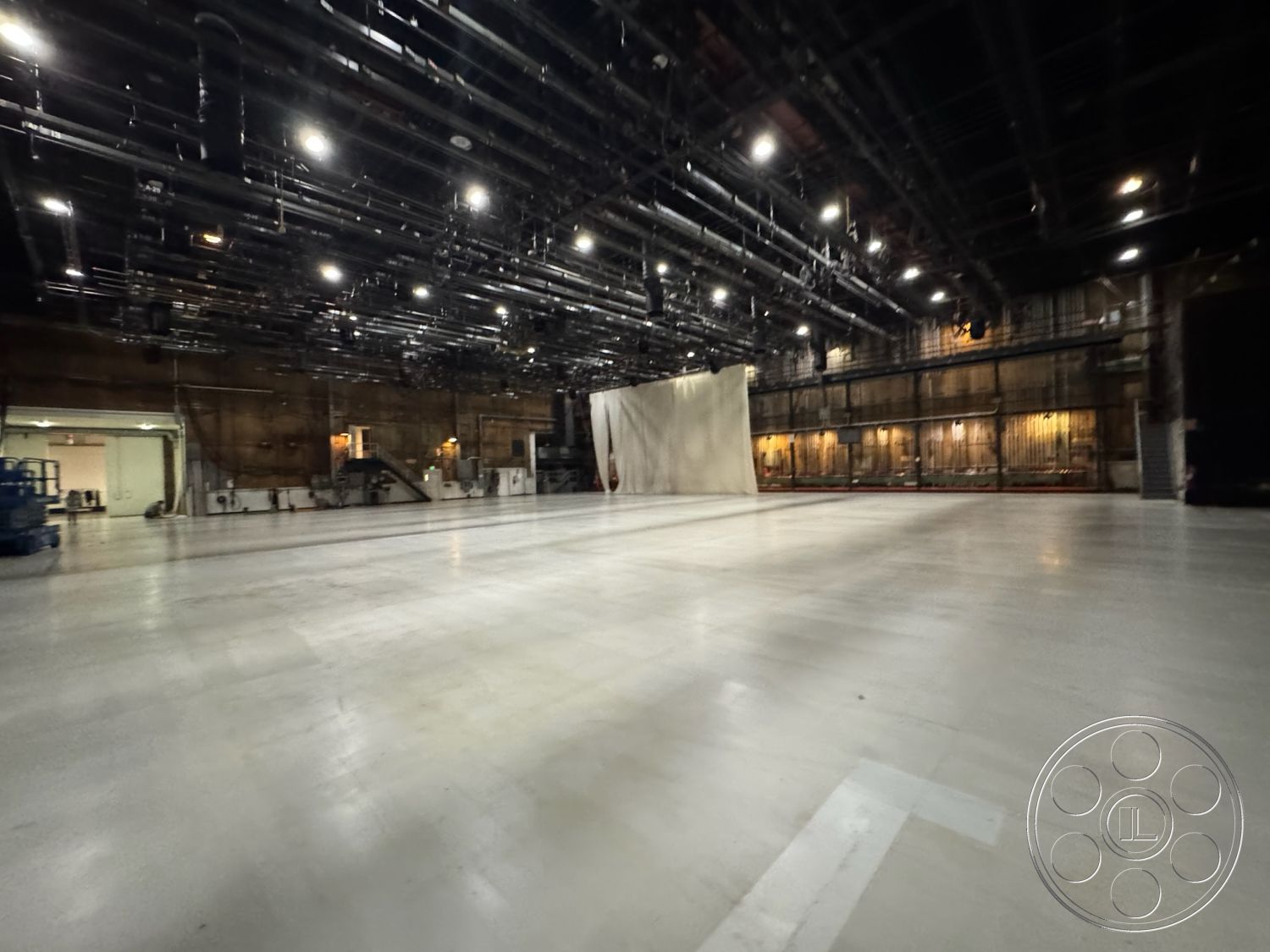 Stage 33 - neutral color palette, concrete floor, open space layout, high ceiling, unfinished walls, flexible workspace, raw materials, exposed ceiling beams, rectangular space, studio environment, ventilation system, large entryway, production facility, bright artificial lighting, urban industrial design, industrial interior, metal piping installation, acoustic soundproofing, floor-to-ceiling wall
