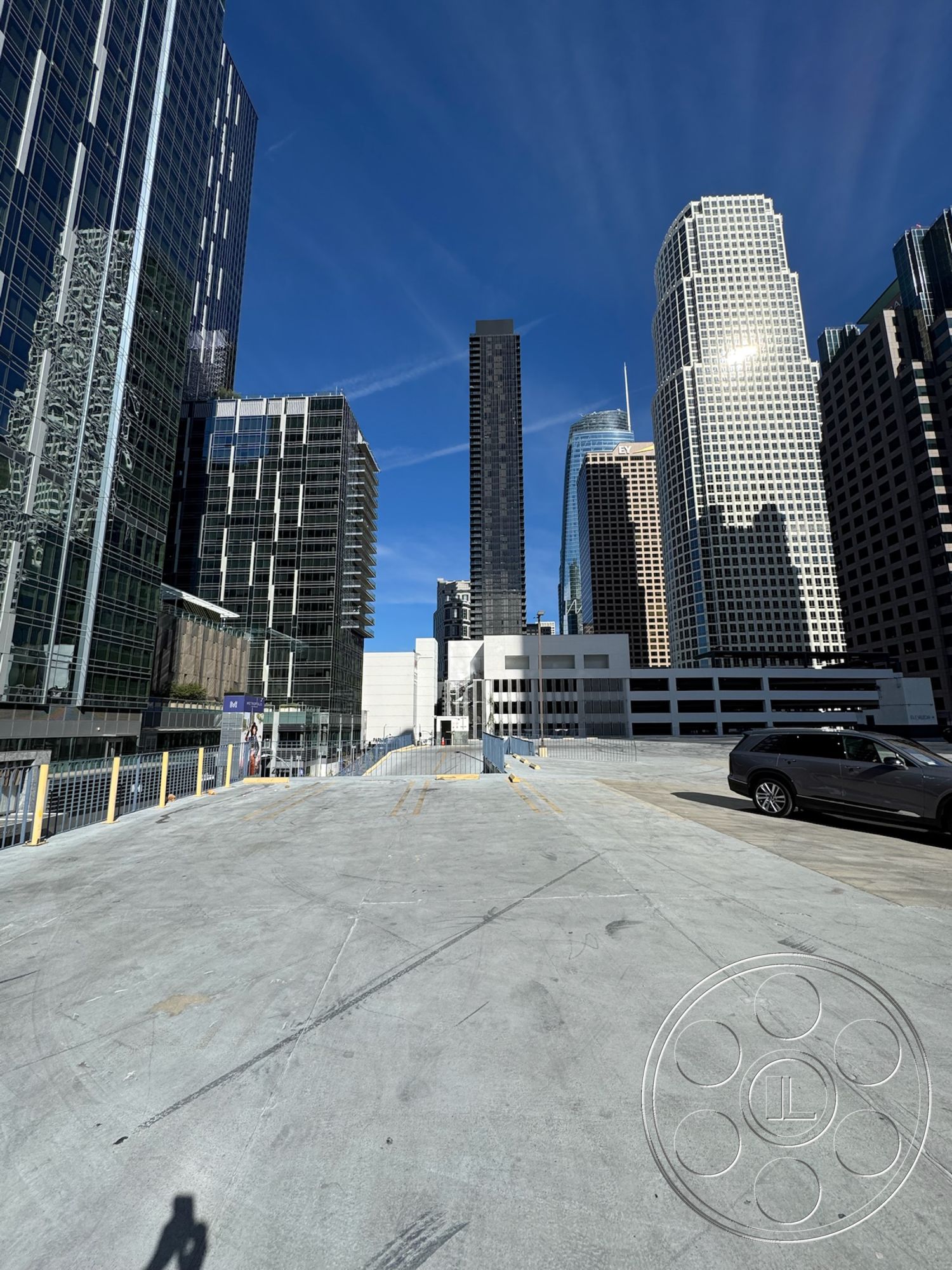 Rooftop 6 - urban skyline view, modern architectural elements, city environment, flat concrete roof, open concrete space, multi-story parking structure, blue sky backdrop, exterior concrete parking garage, high-rise glass building facades, steel and glass skyscrapers, concrete structural supports