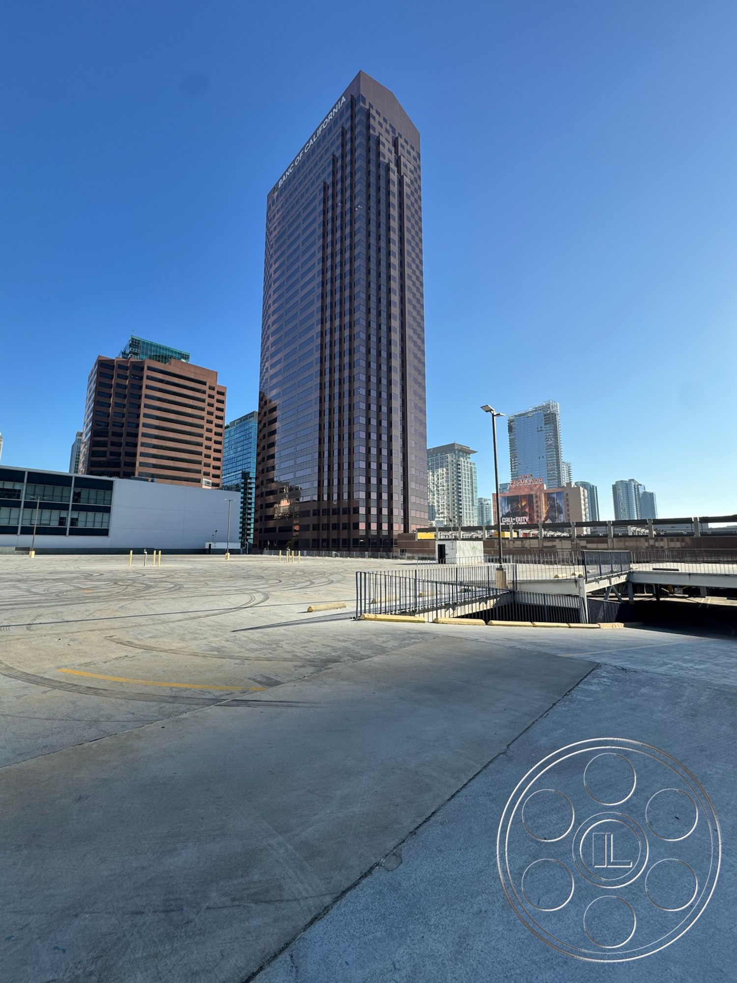 Rooftop 6 - modern architectural style, exterior glass curtain wall, mixed-use development area, curved concrete driveway, concrete pedestrian walkway, exterior reflective glass facade, parking lot concrete surface, high-rise commercial building, urban skyline setting, surrounding cityscape view