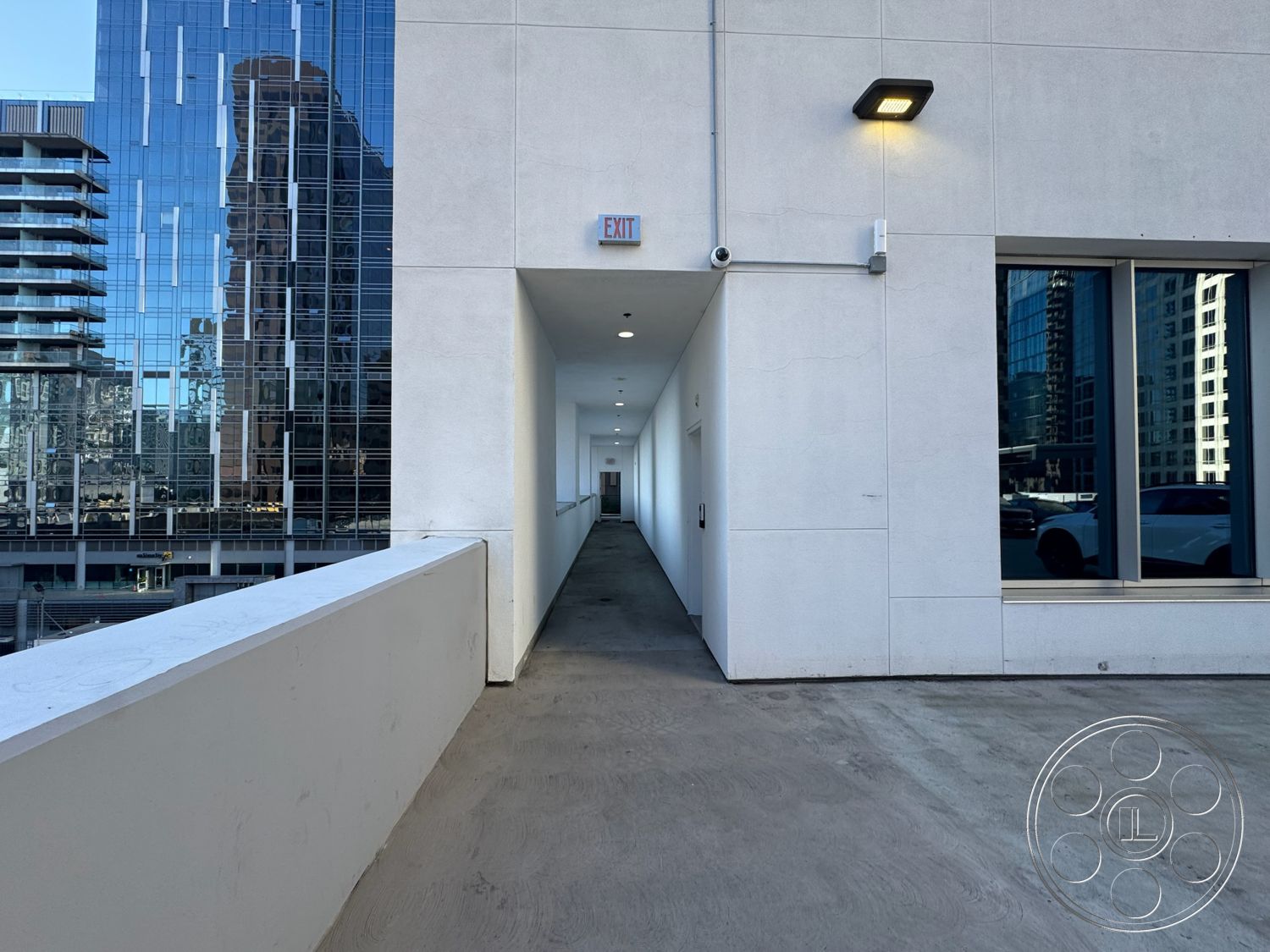 Rooftop 6 - exterior, minimalist aesthetic, modern architectural style, concrete walkway, flat roof design, open balcony design, smooth finish stucco walls, industrial corridor, glass window reflections, accent outdoor lighting, adjacent urban skyline view, sleek building facade