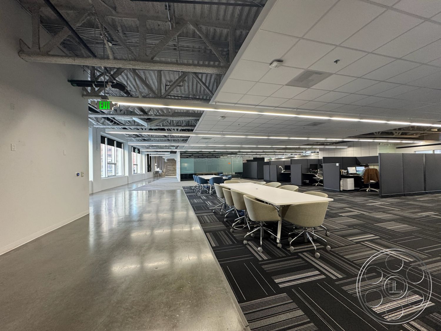 Rooftop 6 - polished concrete flooring, functional workspace, floor-to-ceiling windows, open office layout, shared workspace, glass partition walls, white painted walls, natural light emphasis, textured carpet tiles, contemporary office design, collaborative meeting area, urban office setting, industrial-style interior, LED ceiling lighting, exposed steel ceiling beams, modular office cubicles, task-oriented design