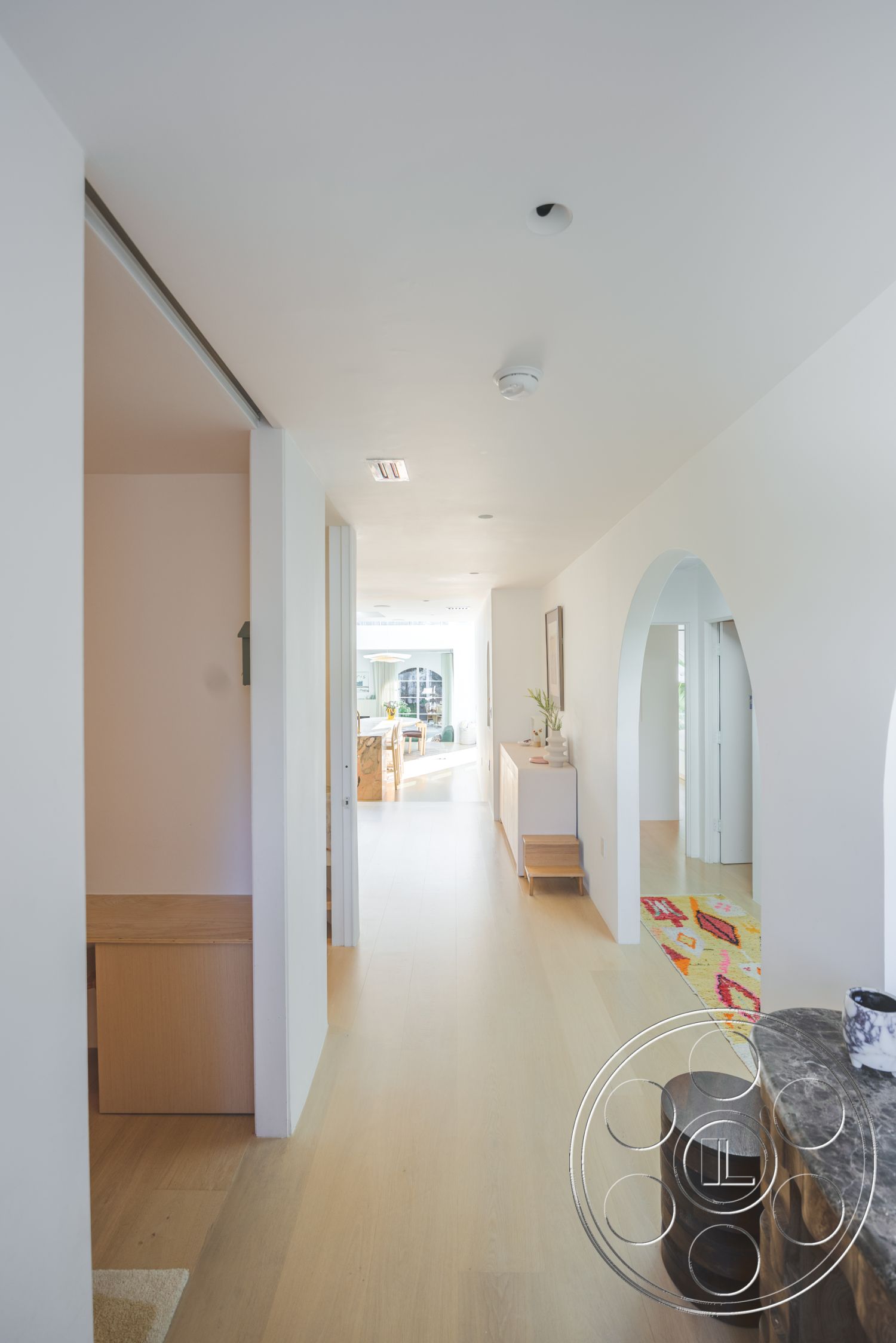 Modern 519 - light wood cabinetry, minimalist furniture, arched doorways, modern minimalist design, natural light through large windows, white textured plaster walls, spacious corridor layout, cohesive color palette, functional entryway space, interior hardwood hallway floors, bright open layout, contemporary accent rug