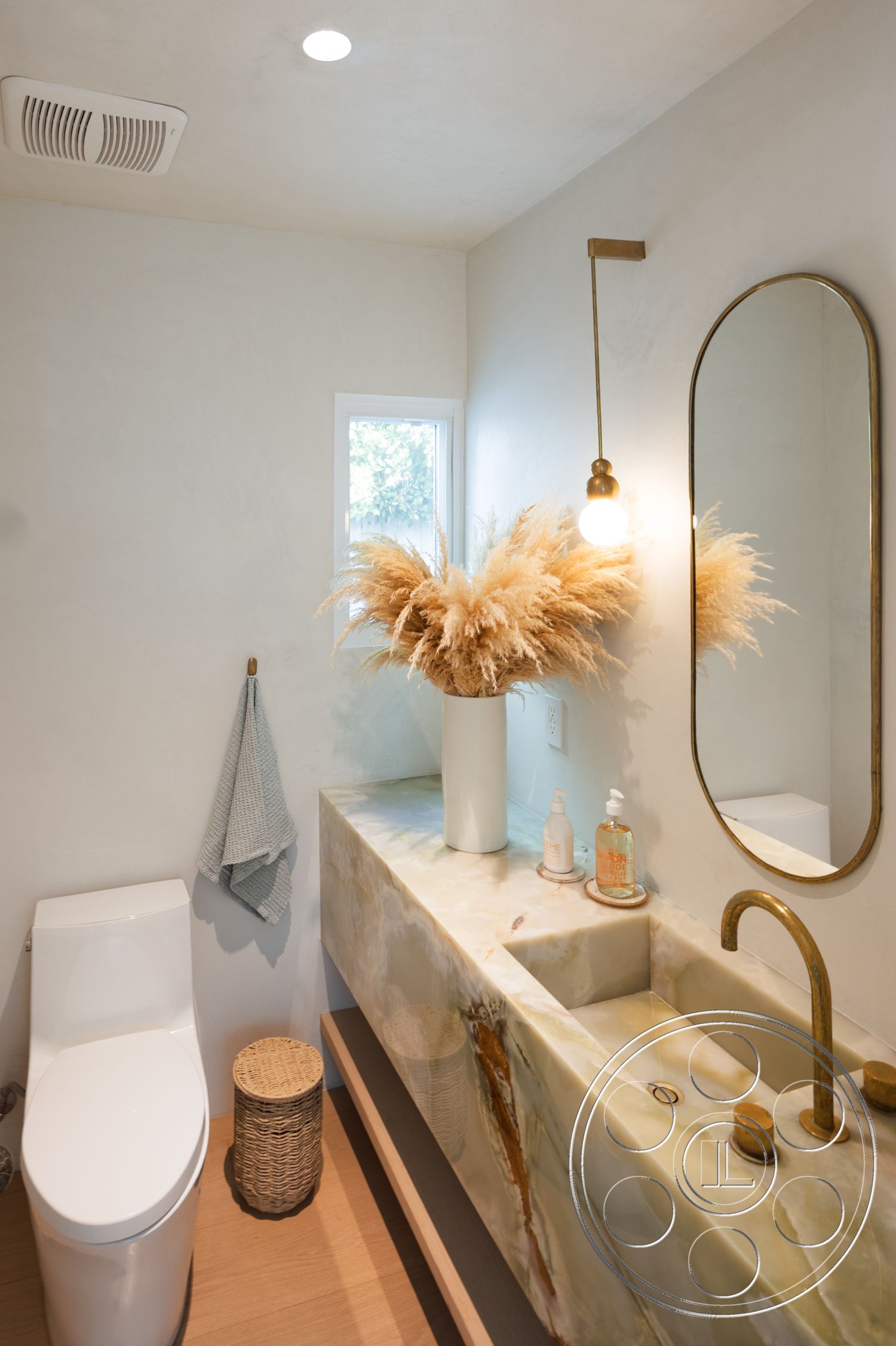 Modern 519 - exterior: natural light bathroom, interior: onyx countertop vanity, interior: wall-mounted round mirror, interior: modern minimalist faucet, interior: polished concrete wall finish, interior: recessed ceiling lighting, interior: woven basket storage, interior: soft texture decor, interior: light wood flooring, interior: tranquil color palette, interior: botanical accents, interior: functional space for small room