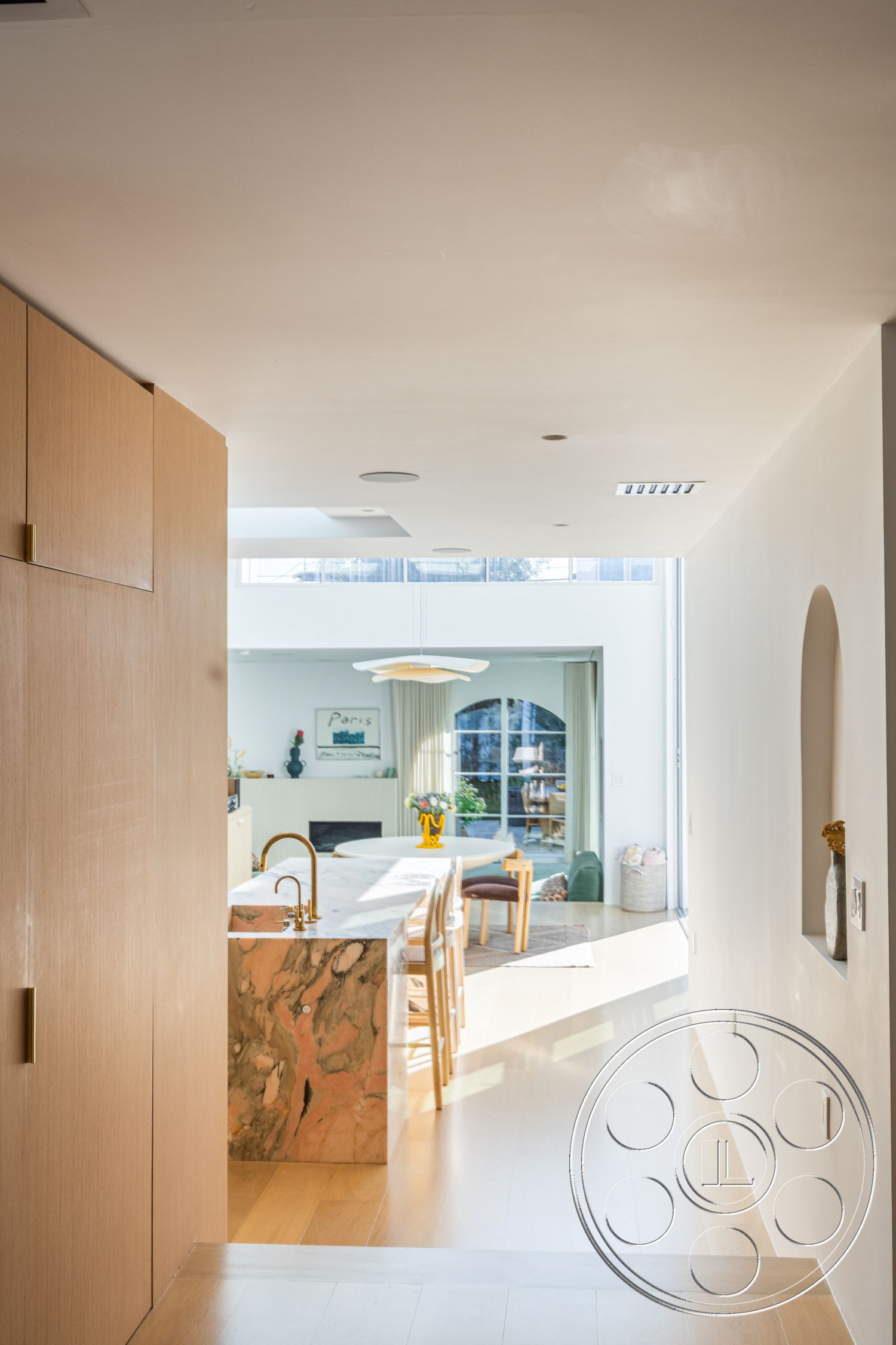 Modern 519 - neutral color palette, minimalist aesthetic, light hardwood flooring, modern pendant lighting, textured wall accents, light wood cabinetry, floor-to-ceiling windows, bright and airy atmosphere, white plaster walls, contemporary interior, open concept living area, natural light flooding the space, subtle recessed lighting, interior hallway design, seating area with modern chairs, marble kitchen island with pink veining, arched doorways to dining area