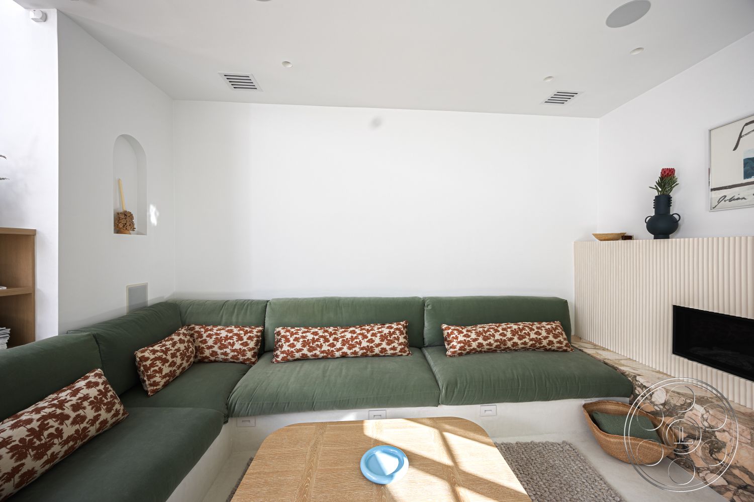 Modern 519 - contemporary artwork, earthy color palette, floor-to-ceiling windows, soft area rug, decorative throw pillows, simple architectural lines, indoor plant decor, light wood coffee table, modern minimalist design, interior living room, textured plaster wall treatment, white painted walls, natural stone fireplace surround, organic decor elements, green velvet sectional sofa, wooden bookshelf unit, rounded niche wall shelf