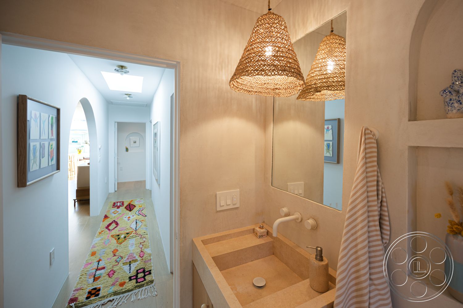 Modern 519 - neutral color palette interior, textured plaster walls interior, recessed lighting fixtures interior, arched doorways interior, minimalist bathroom design interior, natural stone sink countertop interior, woven pendant light fixtures interior, hardwood hallway flooring interior, colorful patterned area rug interior, framed artwork on gallery wall interior, open hallway leading to living space interior, skylight providing natural light interior, built-in shelving for decor interior