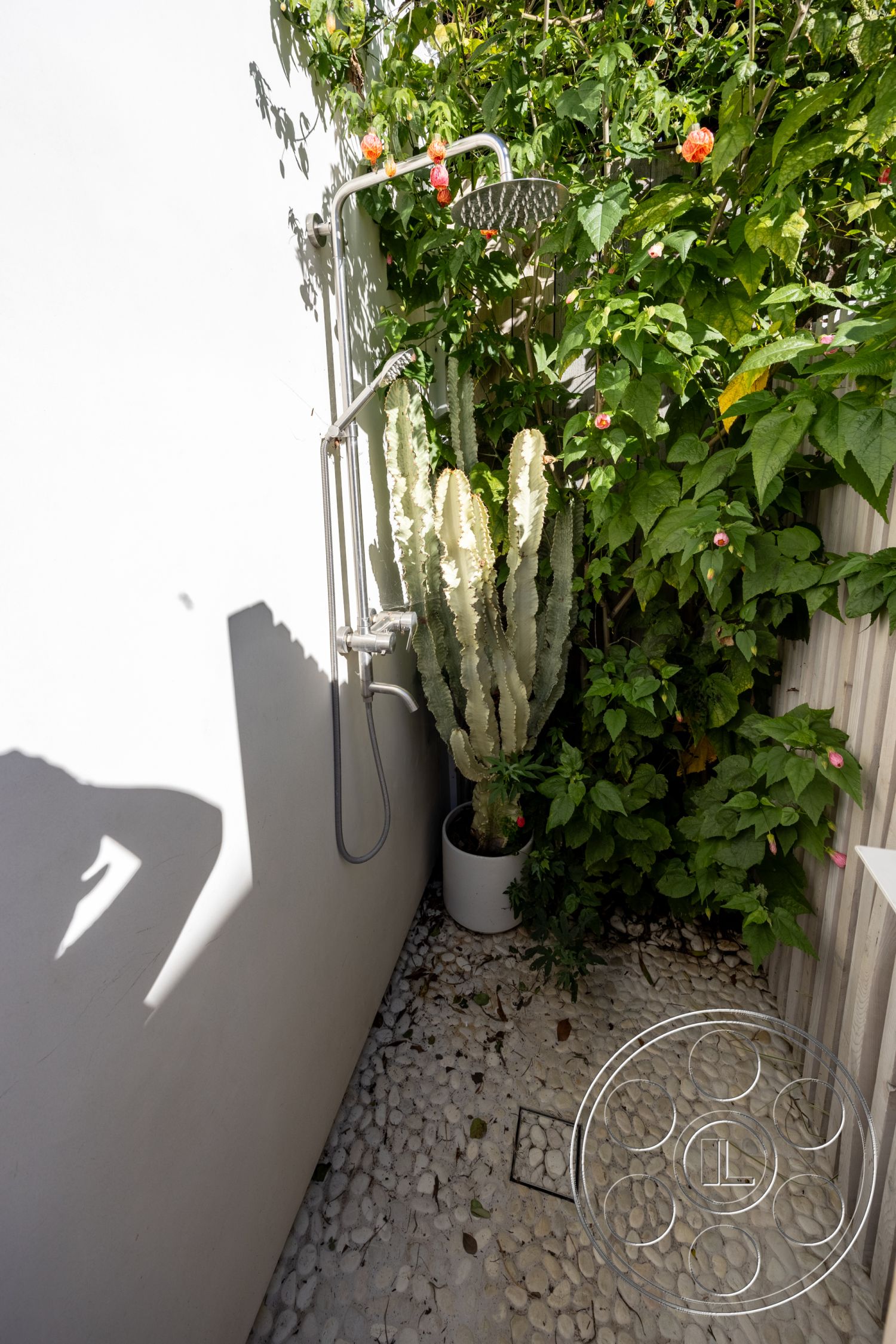 Modern 519 - exterior, outdoor shower, vertical garden, rustic landscaping, modern minimalist design, stainless steel shower fixtures, smooth white wall, pebble stone shower flooring, lush greenery surrounding shower, potted cactus, cement perimeter wall, natural elements integration, plant-based privacy screen