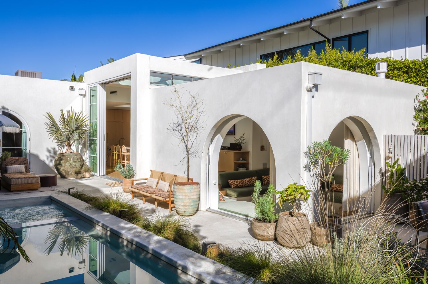 Modern 519 - rectangular swimming pool, open-concept living space, arched doorways, concrete pool deck, wooden outdoor furniture, desert surroundings, exterior stucco walls, minimalist architecture style, floor-to-ceiling glass doors, natural light flooding interior, modern outdoor landscaping, stylish outdoor seating area, potted plants in natural stone planters, sunny garden patio, light wood dining furniture, modern guest area, poolside relaxation space, spacious exterior patio, greenery accentuating outdoor space