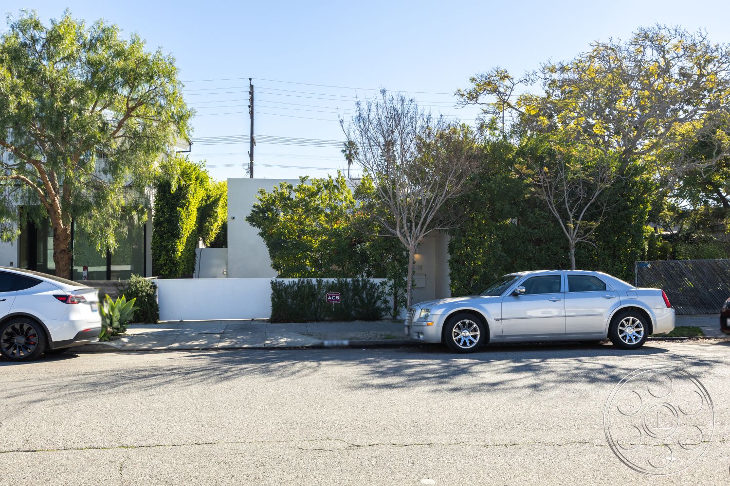 Modern 519 - privacy hedge, concrete driveway, urban residential area, paved sidewalk, landscaped garden setting, modern minimalist design, exterior white stucco walls, decorative stone border, flat roof architecture, multiple vehicle accommodation, open garage space, mature trees for shade, light-colored exterior finish
