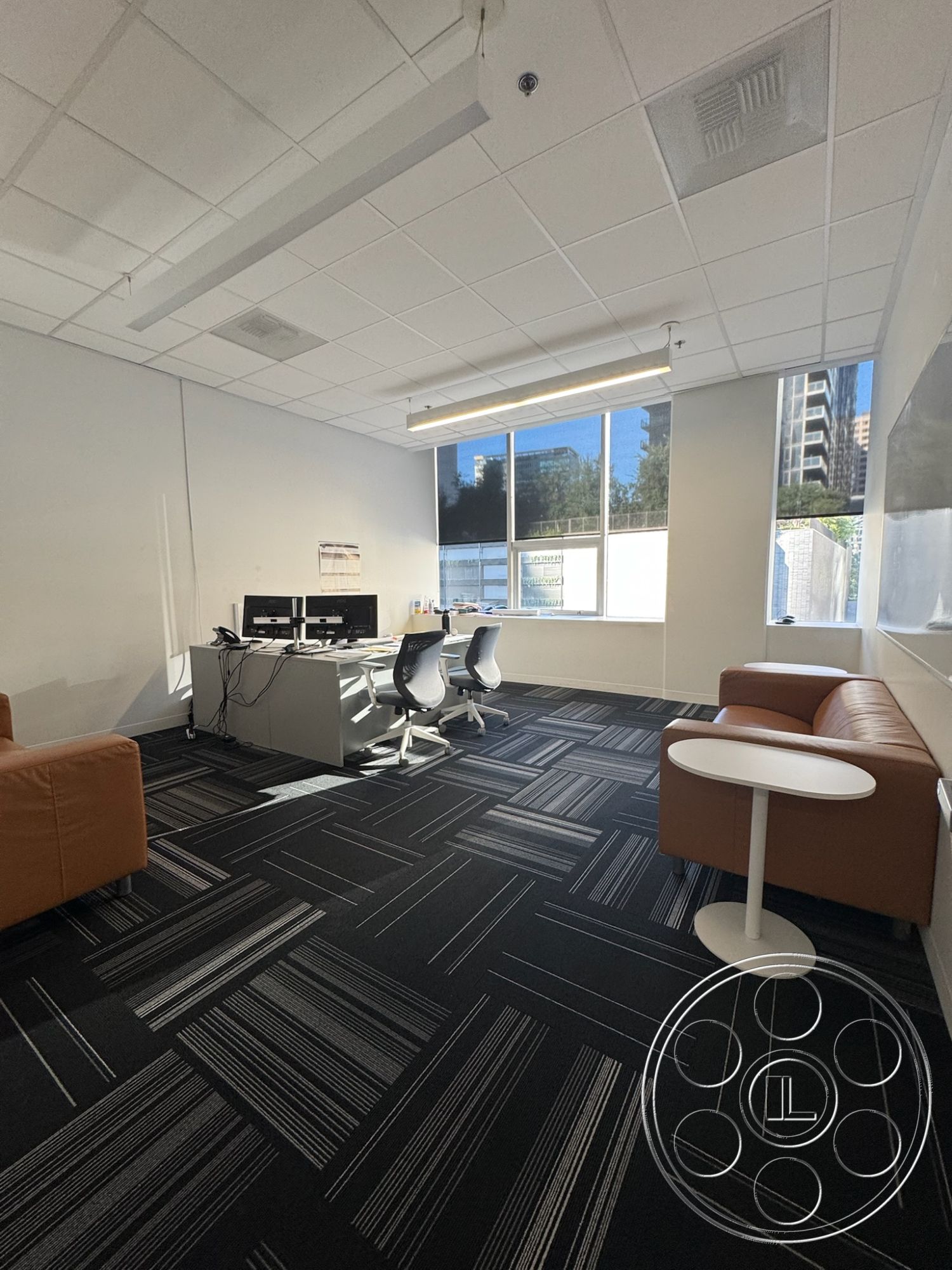 Office 128 - minimalist design elements, brown leather sofas, ergonomic office chairs, textured carpet flooring, natural light ambiance, interior office space, modern office furniture, large windows with city view, drop ceiling with fluorescent lights, black and white striped carpet tiles, white drywall walls, open work area layout, round white side tables, contemporary workstation