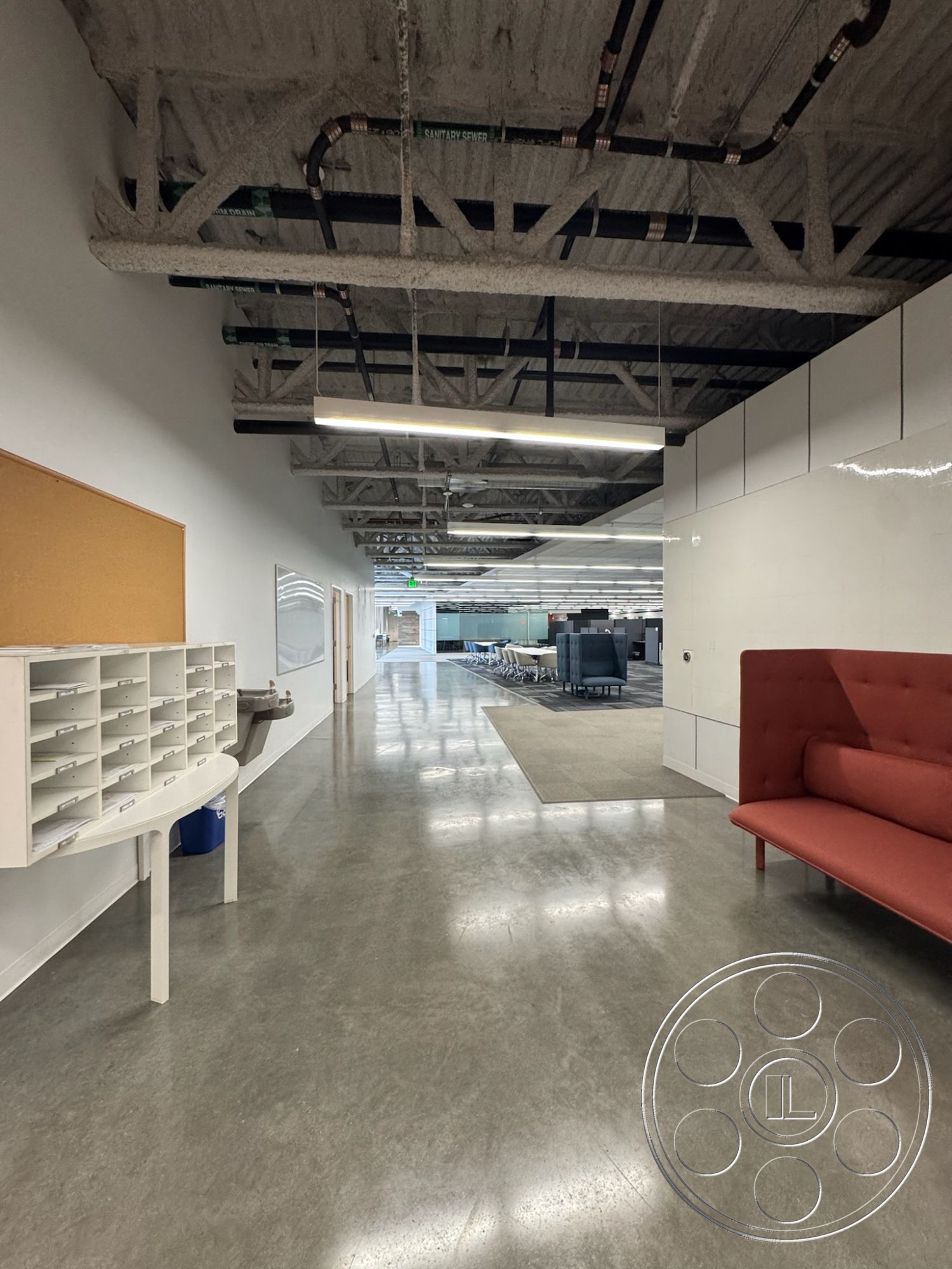 Office 128 - polished concrete flooring, commercial space, open office layout, acoustic ceiling tiles, glass partition walls, minimalist design details, white painted walls, modern lounge seating, modern furniture design, collaborative work areas, interior workspace, exposed metal ceiling beams, industrial style lighting fixtures, functional office environment, curved reception desk, office corridor