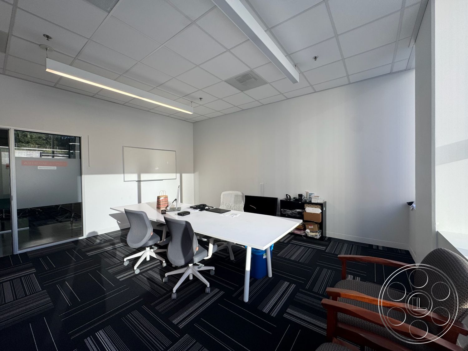 Office 128 - collaborative workspace, linear LED lighting, window with natural light, neutral color scheme, ergonomic office chairs, glass partition walls, white painted walls, interior office space, drop ceiling tiles, carpet office flooring, minimalist office design, office conference table, black and white striped carpet, office storage cabinet