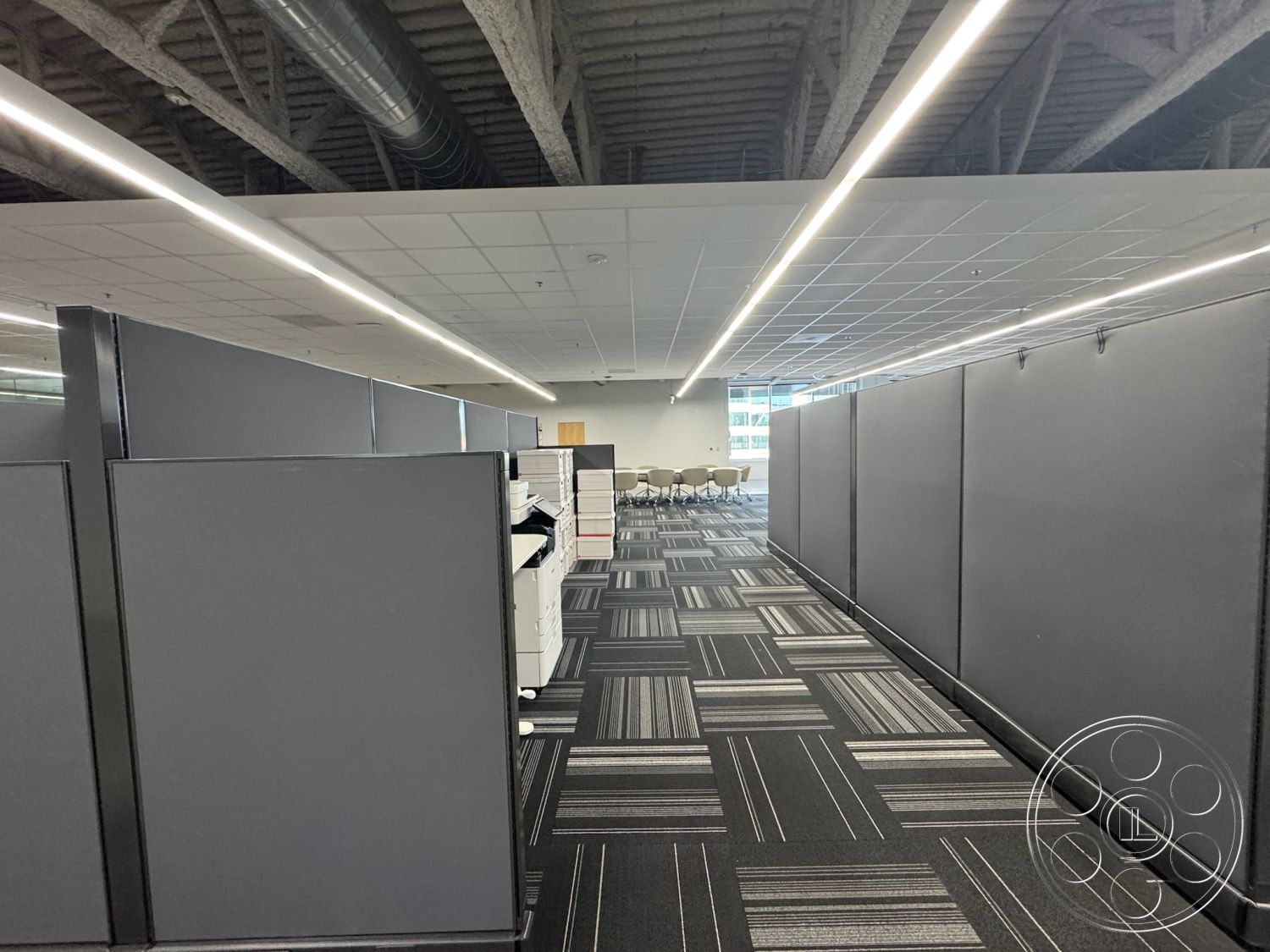 Office 128 - functional workspace, floor-to-ceiling windows, black and gray color scheme, acoustic ceiling panels, open floor plan layout, LED recessed lighting, modern office design, interior office space, collaborative work environment, carpet tile flooring, industrial-style ceiling beams, modular cubicle partitions, meeting area with round table