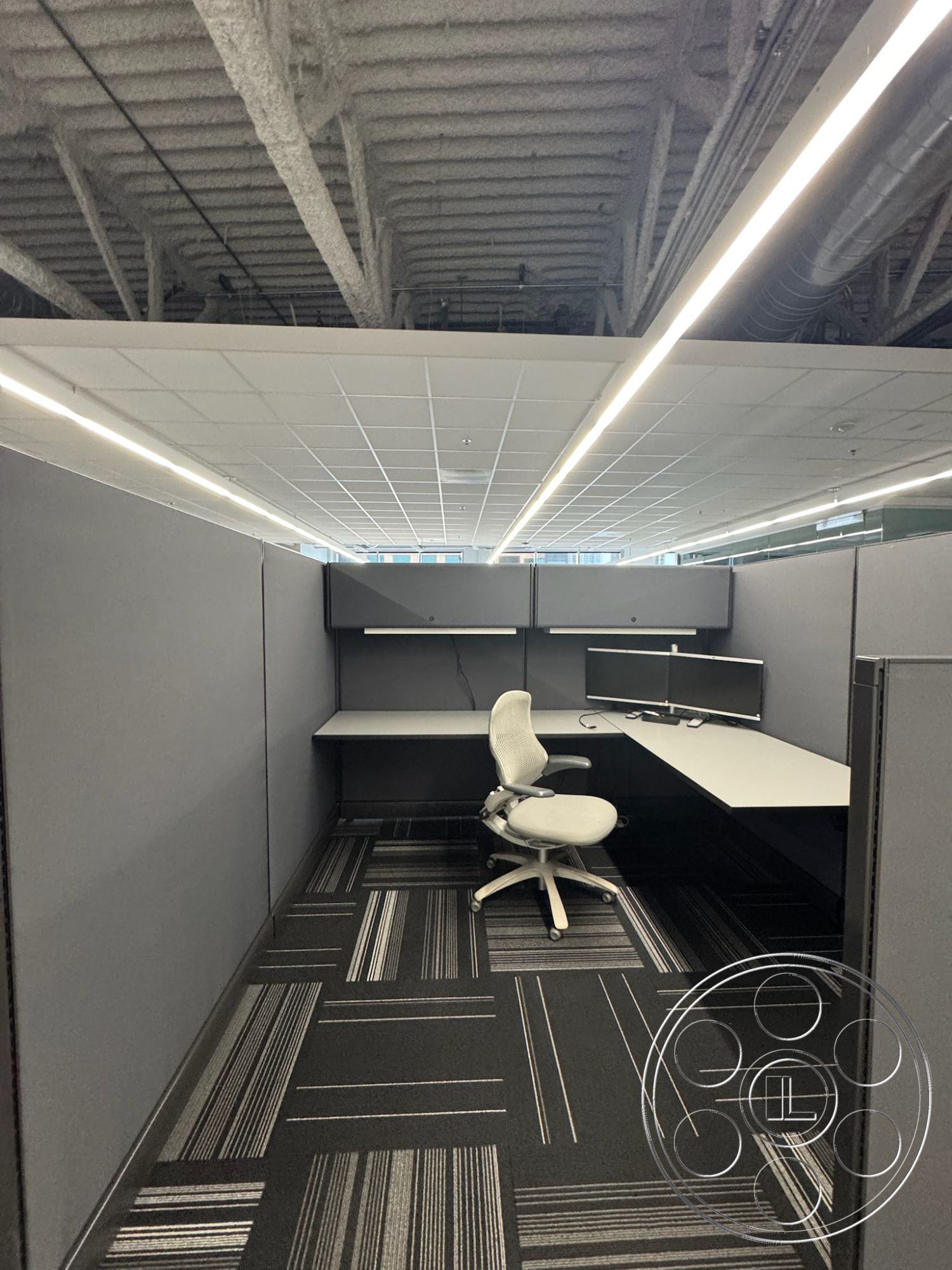 Office 128 - contemporary lighting fixtures, ergonomic office chair, acoustic ceiling tiles, open floor plan layout, modular office furniture, striped carpet flooring, suspended linear LED lighting, gray fabric partition walls, interior office cubicle, textured drop ceiling, L-shaped desk workstation, dual monitor setup, minimalistic office design, collaborative workspace elements