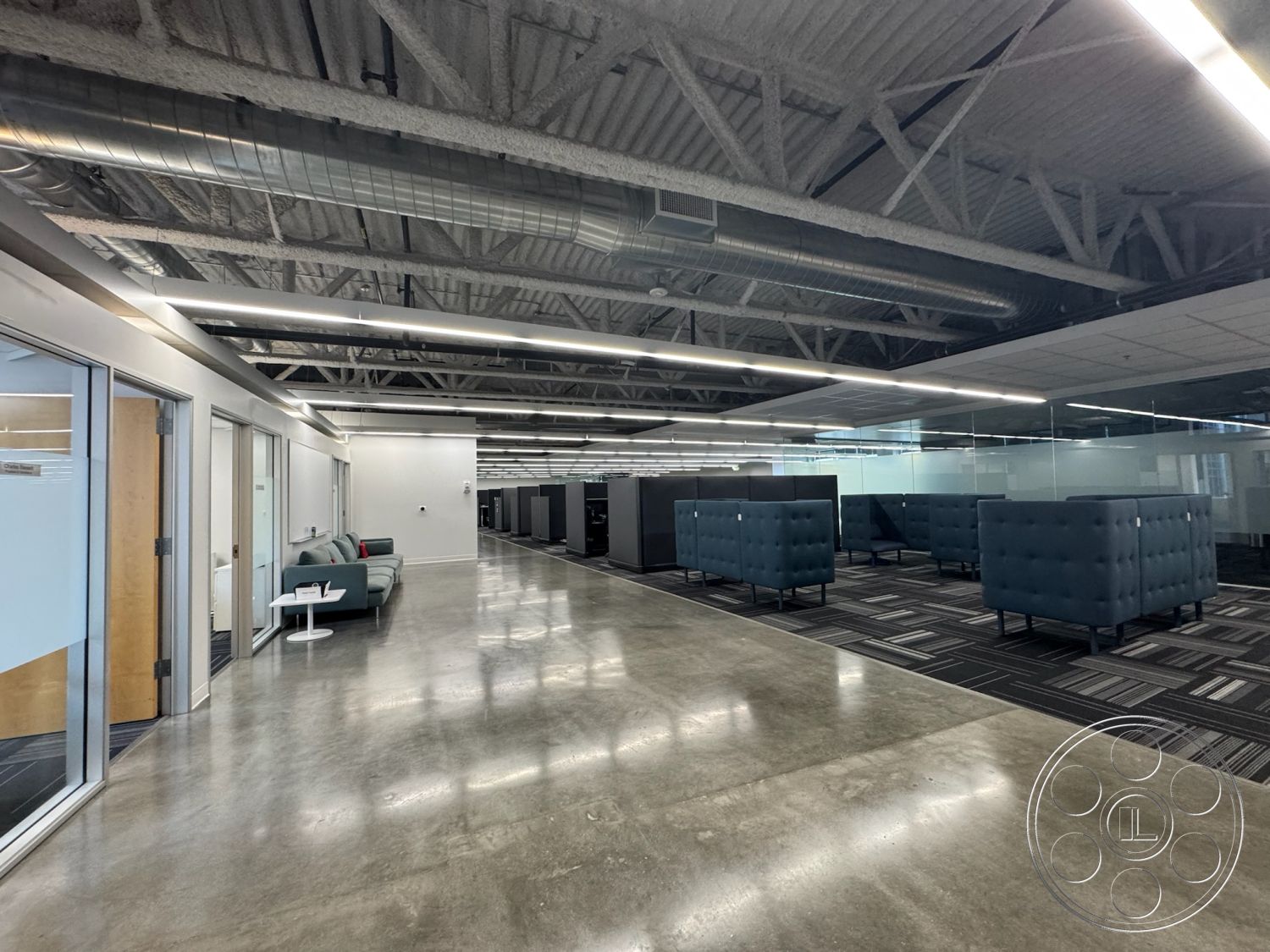 Office 128 - neutral color palette, soft seating, polished concrete flooring, glass doors, collaborative workspace, linear LED lighting, modern lounge area, acoustic ceiling tiles, glass partition walls, textured carpet tiles, industrial style architecture, cubicle workstations, open concept office layout, exposed metal ductwork, interior office design