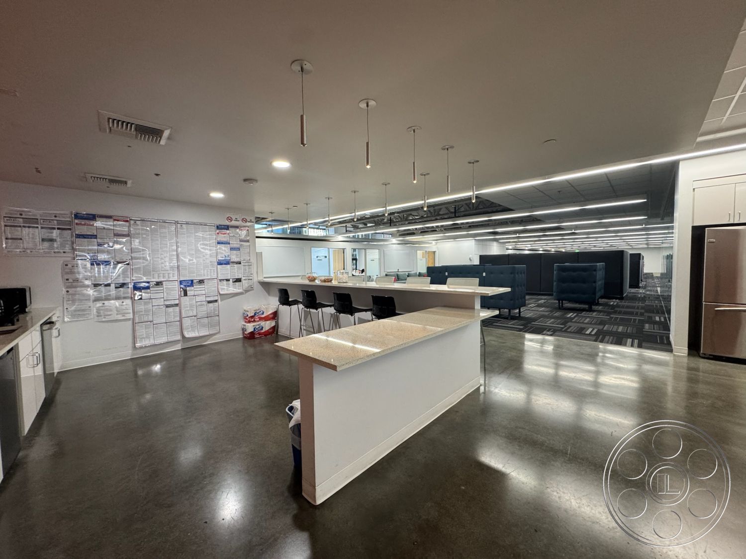 Office 128 - polished concrete flooring, interior space, granite countertop, stainless steel refrigerator, modern bar stools, open office layout, glass partition walls, recessed lighting fixtures, white painted walls, acoustic office cubicles, LED ceiling strip lights, industrial style kitchen area, informational notice board