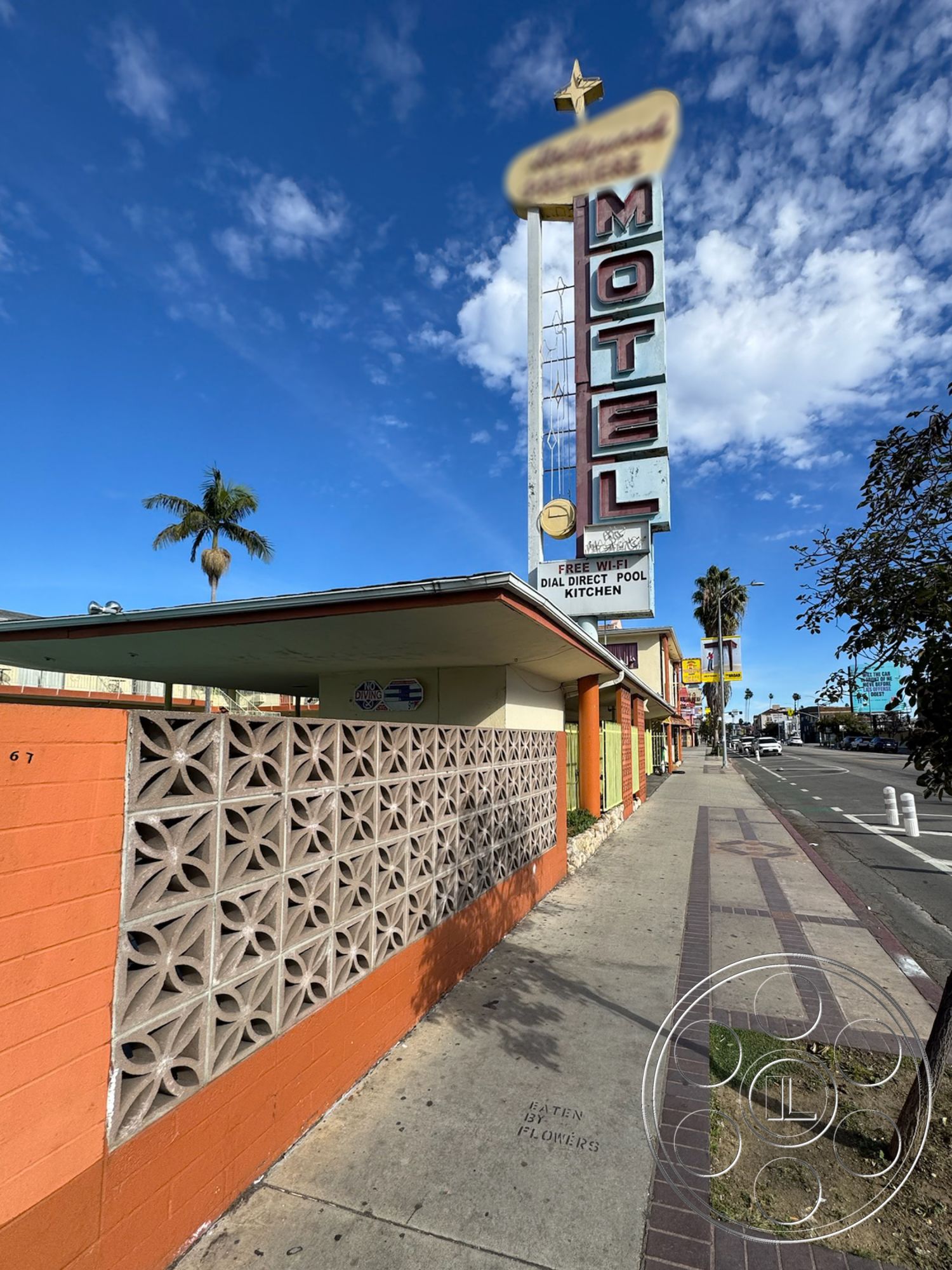 Hotel 59 - exterior, urban environment, city street view, two-story structure, palm tree landscaping, decorative concrete block wall, sunny sky backdrop, retro motel signage, motel facade, colorful stucco exterior, orange painted walls, brick sidewalk, vintage motel aesthetic, direct pool access, dial direct kitchen